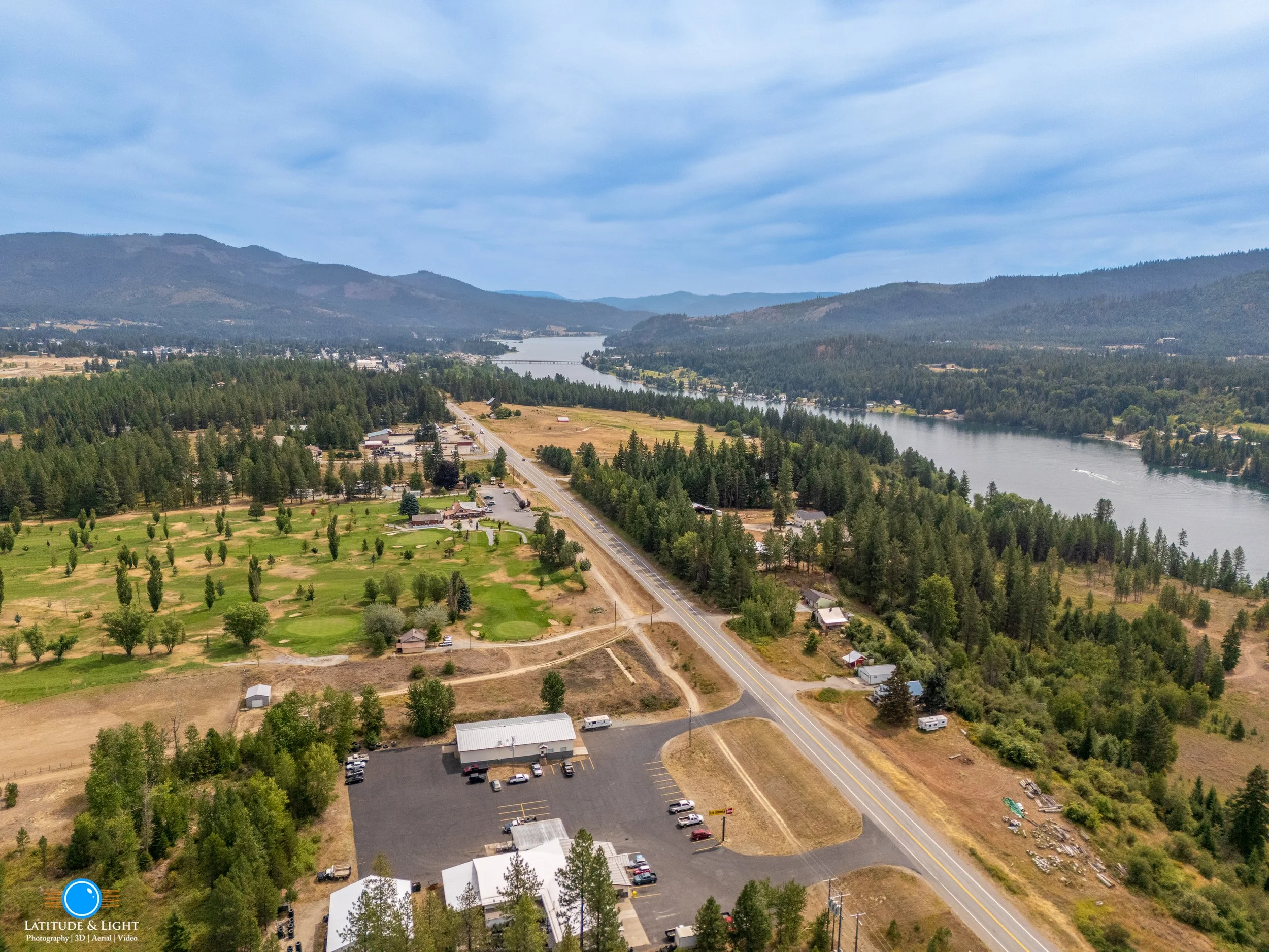 Priest River, Idaho: Aerial view of a rural landscape with a river, forested hills, and sparse buildings and roads.