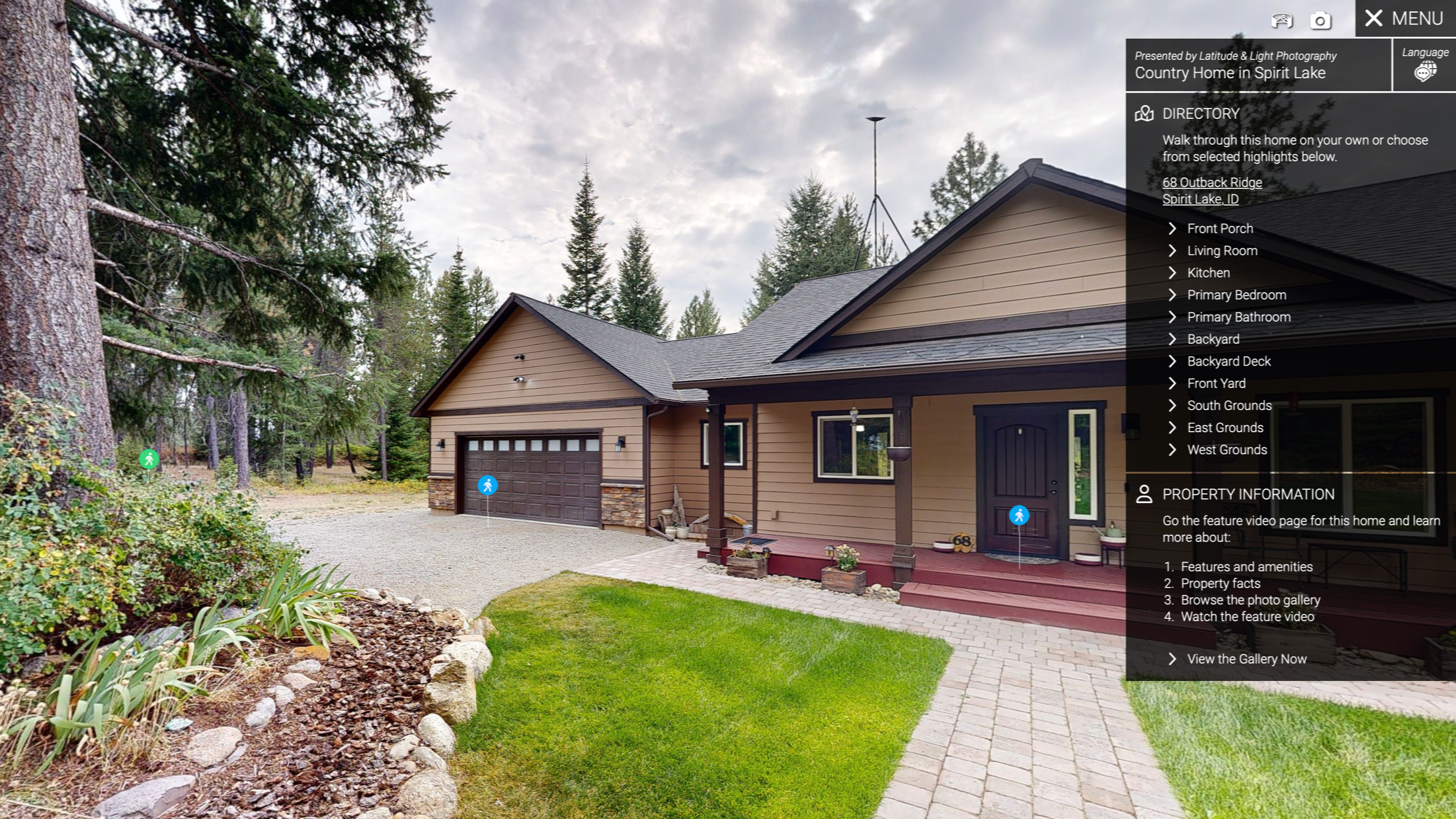 A modern house in north Idaho with a forested area with a brown garage door, a small porch with red steps, and green lawn, surrounded by tall pine trees under a cloudy sky.