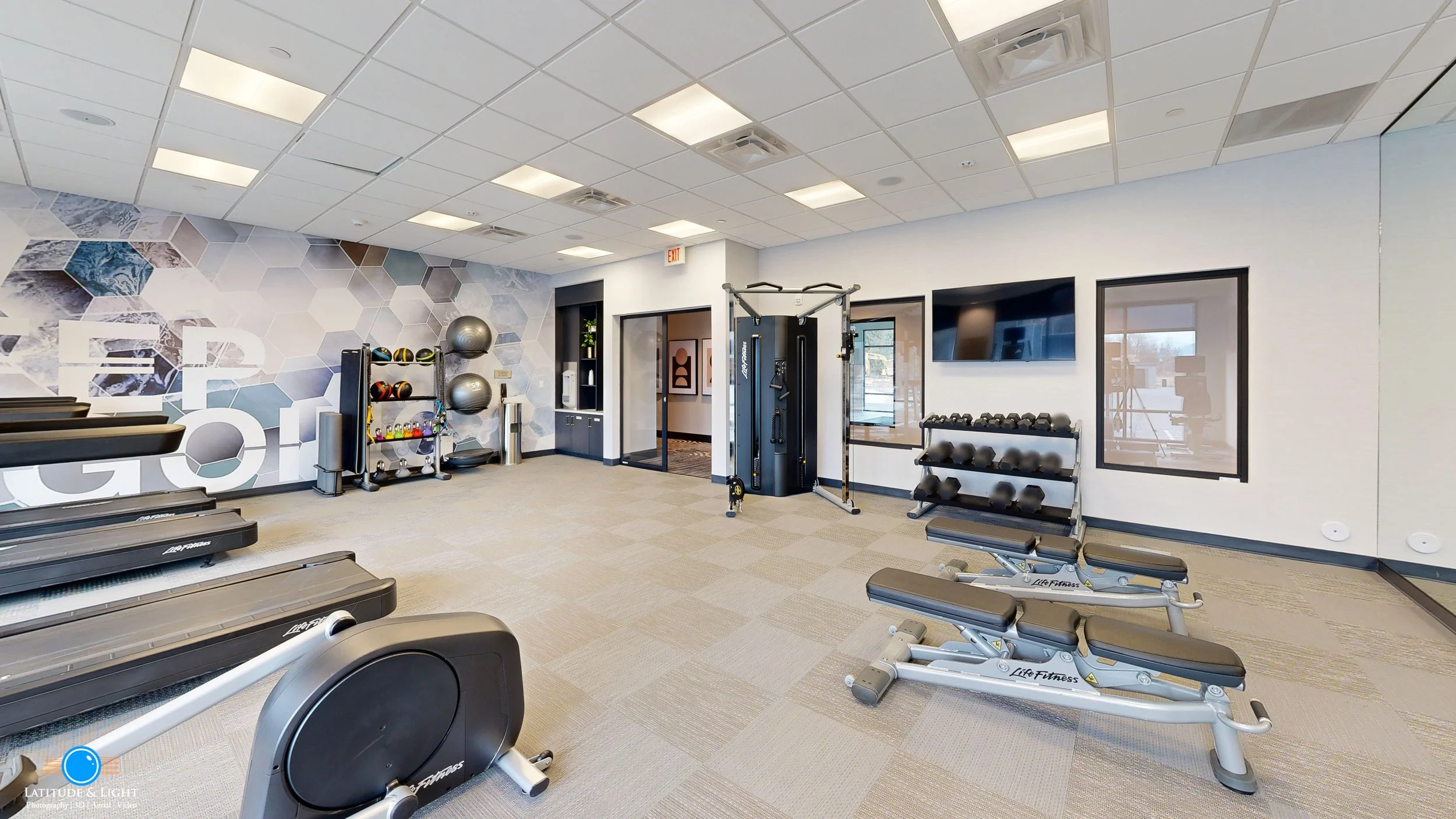 Empty fitness room with treadmills, yoga balls, dumbbells, and exercise equipment.