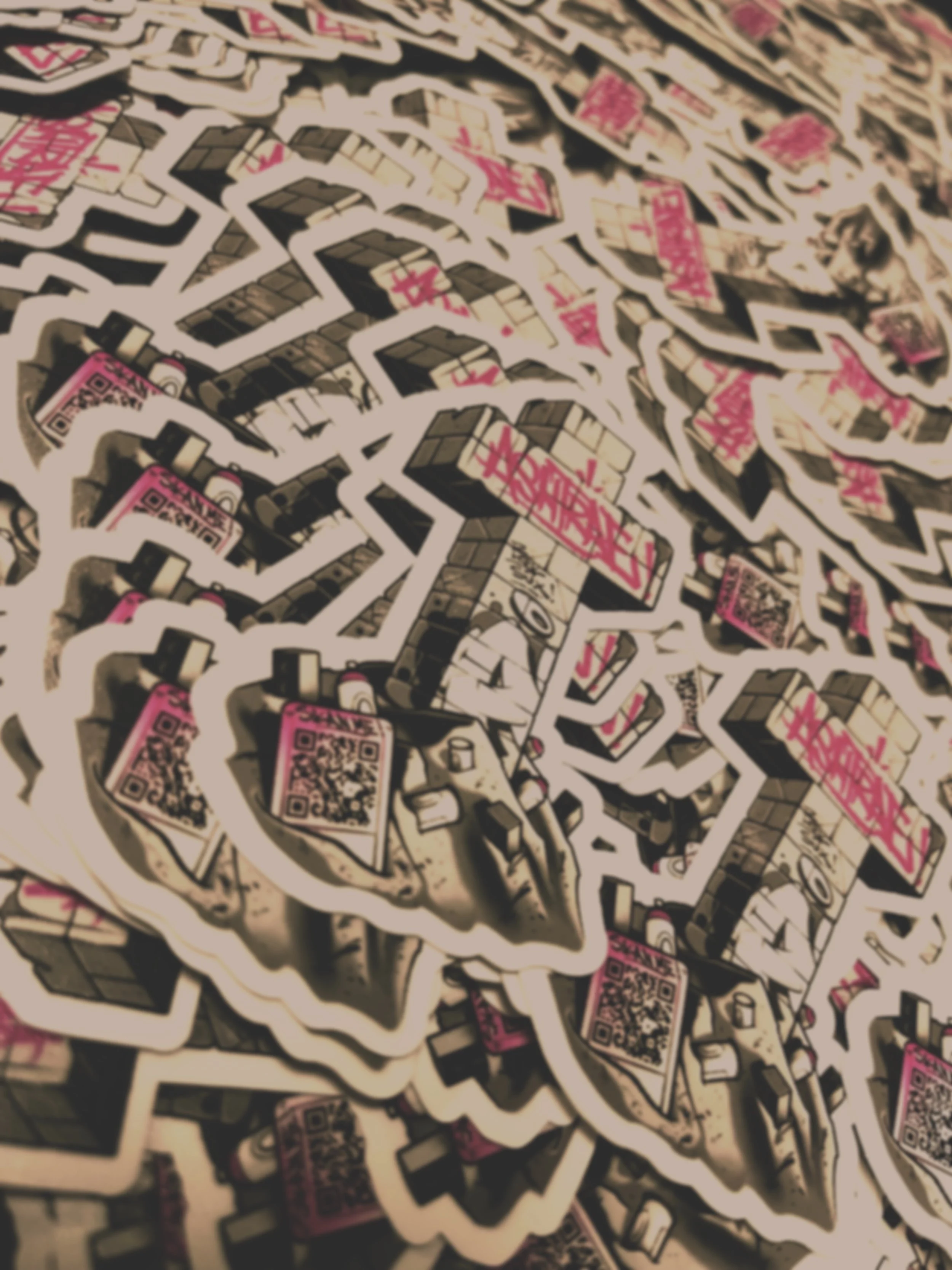 A collection of stickers featuring QR codes, graffiti-style and geometric designs, layered randomly on a surface.