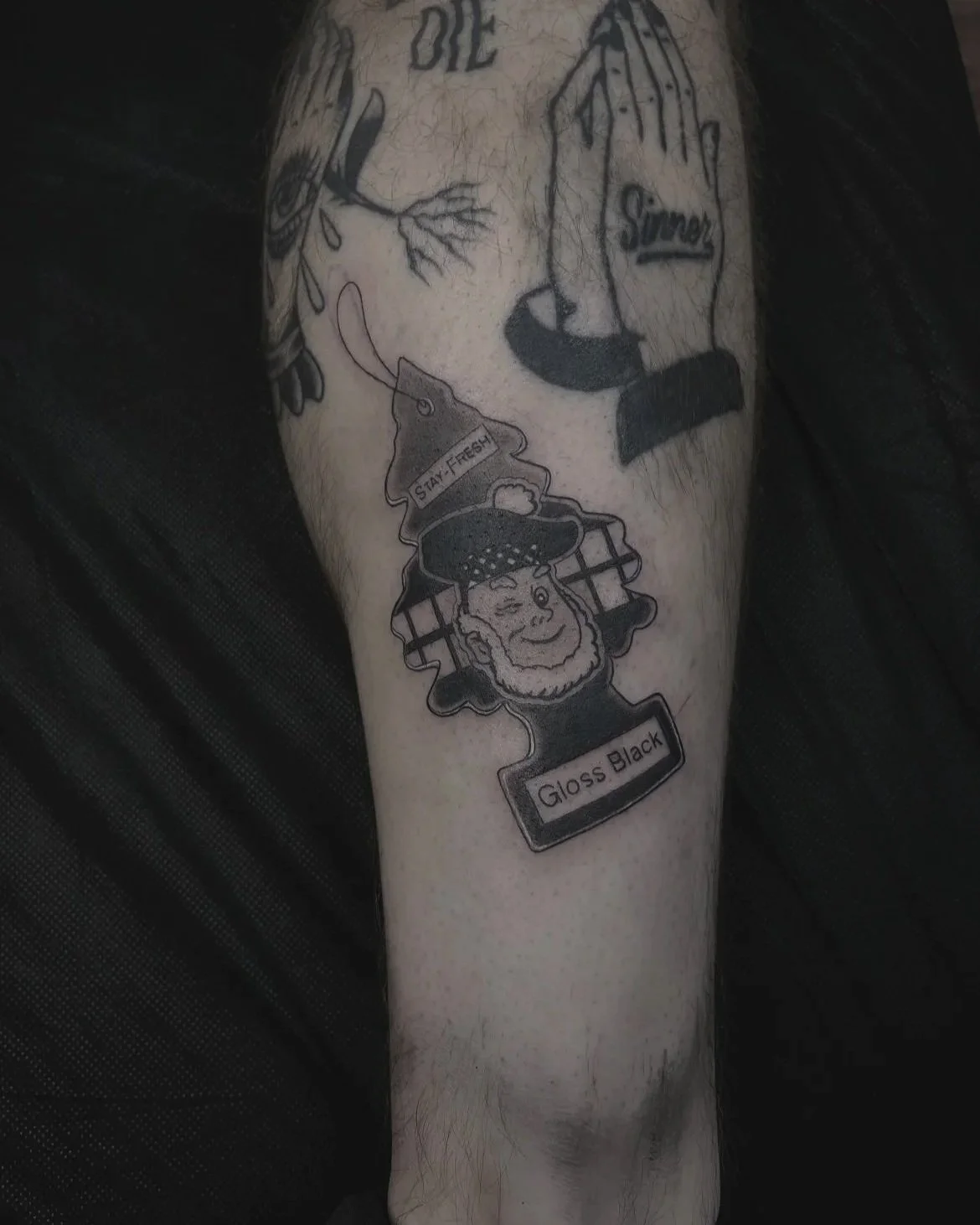 Tattoo featuring a stylized Rustoleum mascot,  with a mustache and eye closed,  and a sign that says 'GLOSS BLACK'.