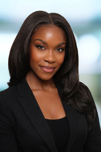 Professional woman with long dark hair wearing a black blazer and smiling