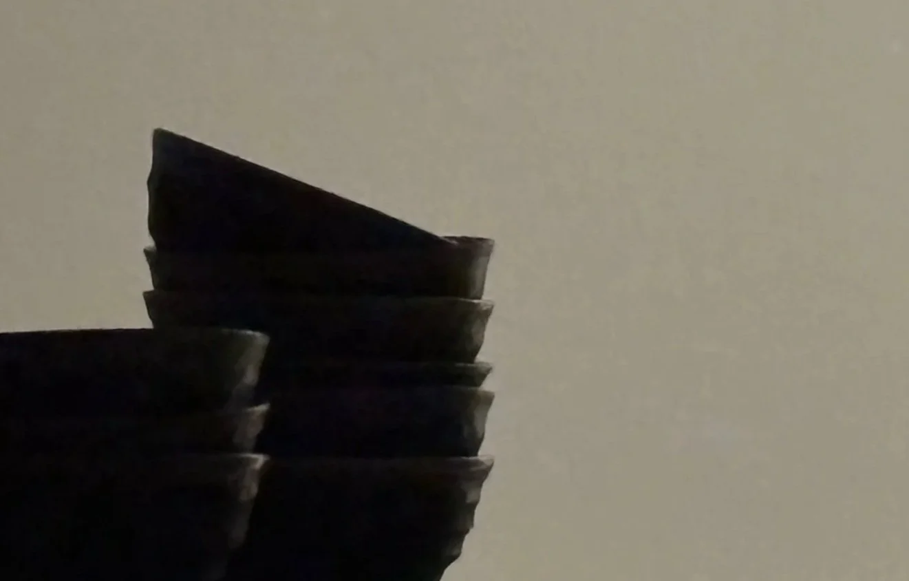 Stacked black bowls against a plain light-colored background.