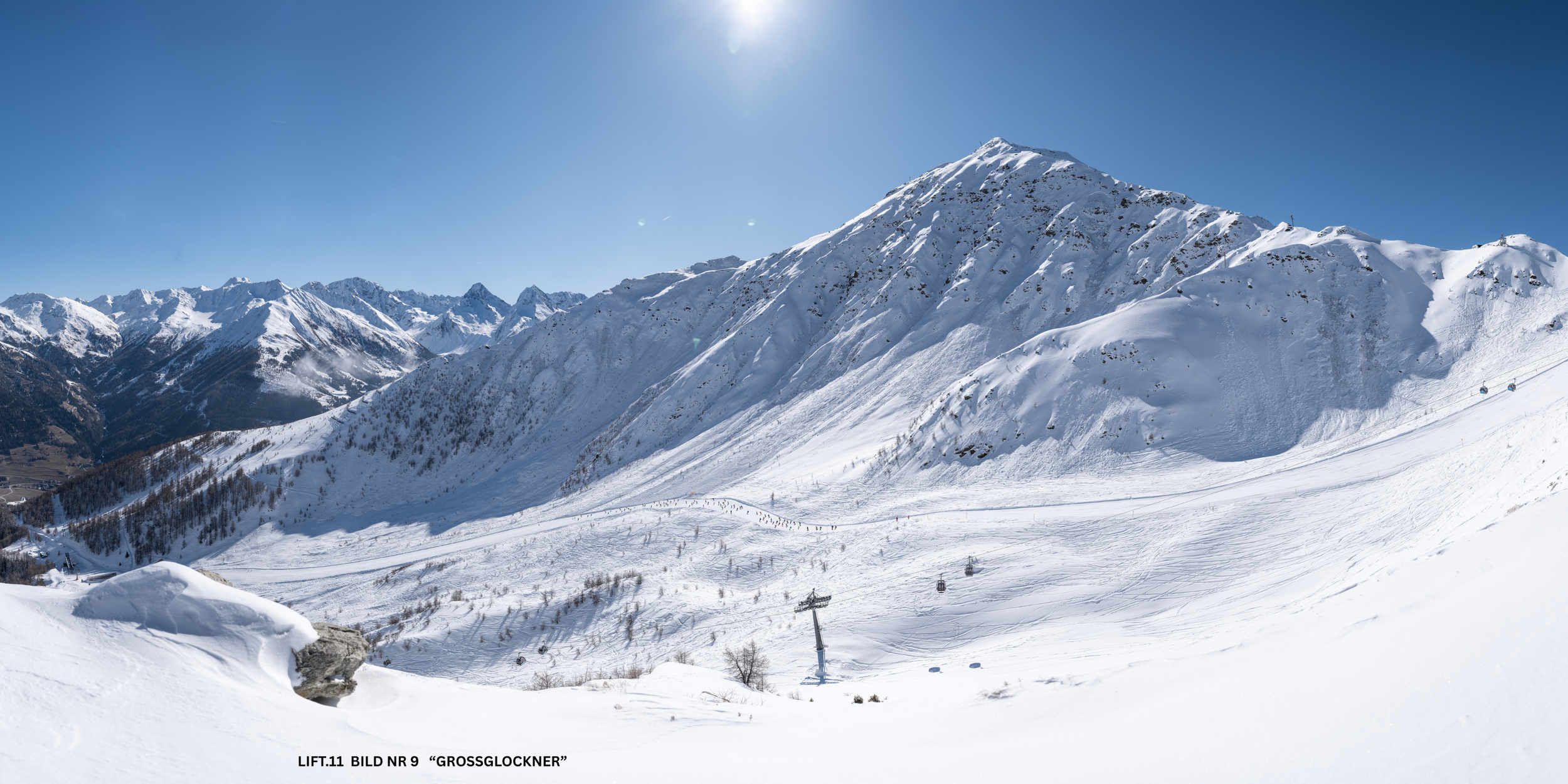 Schneebedeckte Berge bei schönem Himmel mit Skiliften im Vordergrund.