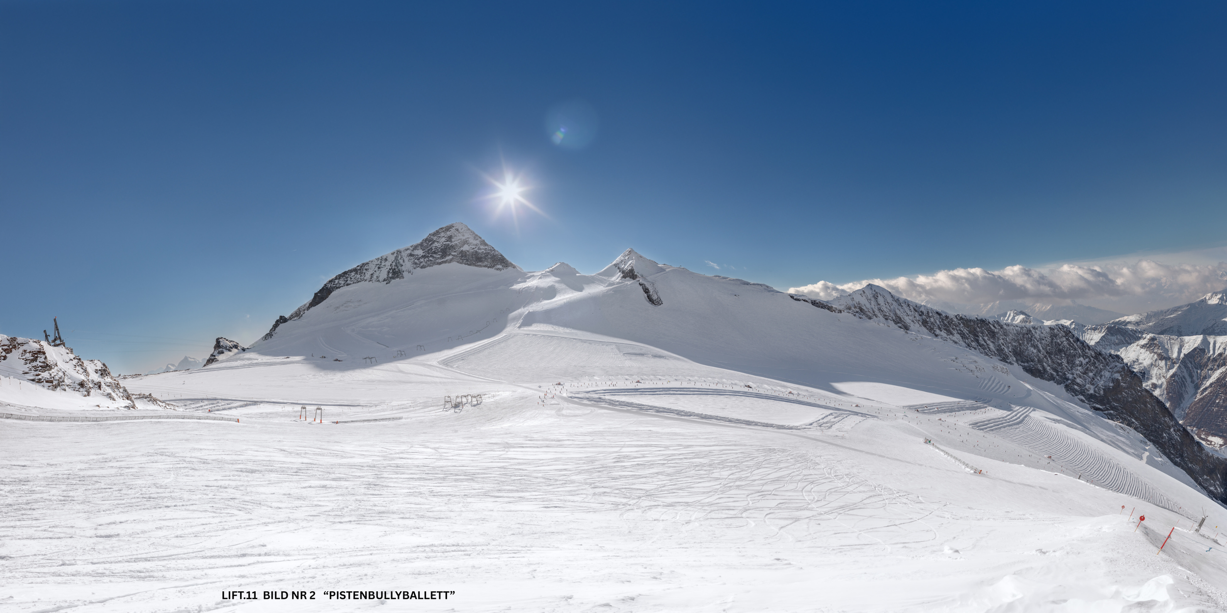 Schneebedeckte Berge bei strahlendem Sonnenschein, Ski- und Snowboardpisten im Vordergrund, klare blaue Himmel, winterliches Bergpanorama.