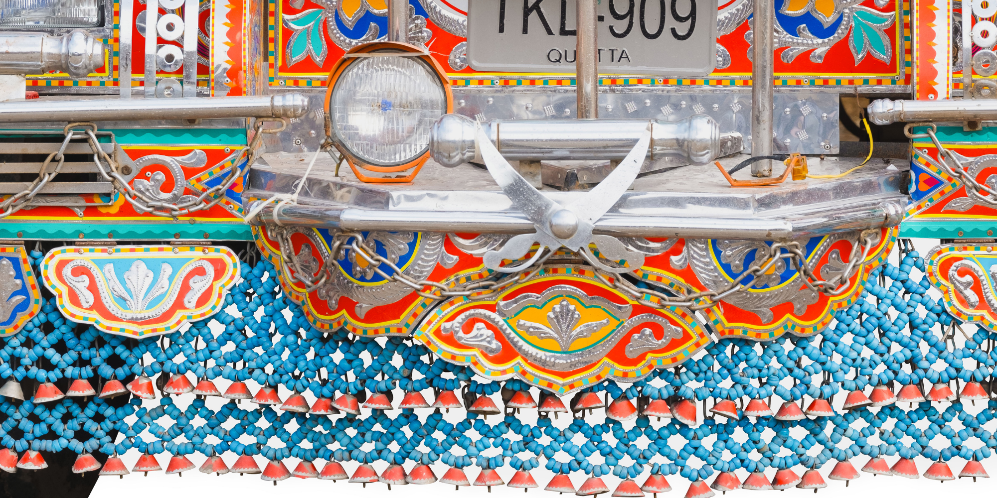 Detailansicht eines bunten Karussells mit Dekorationen aus bunten Perlen, Metallteilen und einem Nummernschild.