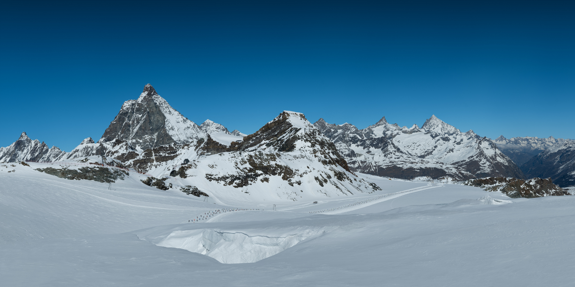 Schneebedeckte Berge unter klarem blauen Himmel in einer Winterlandschaft.