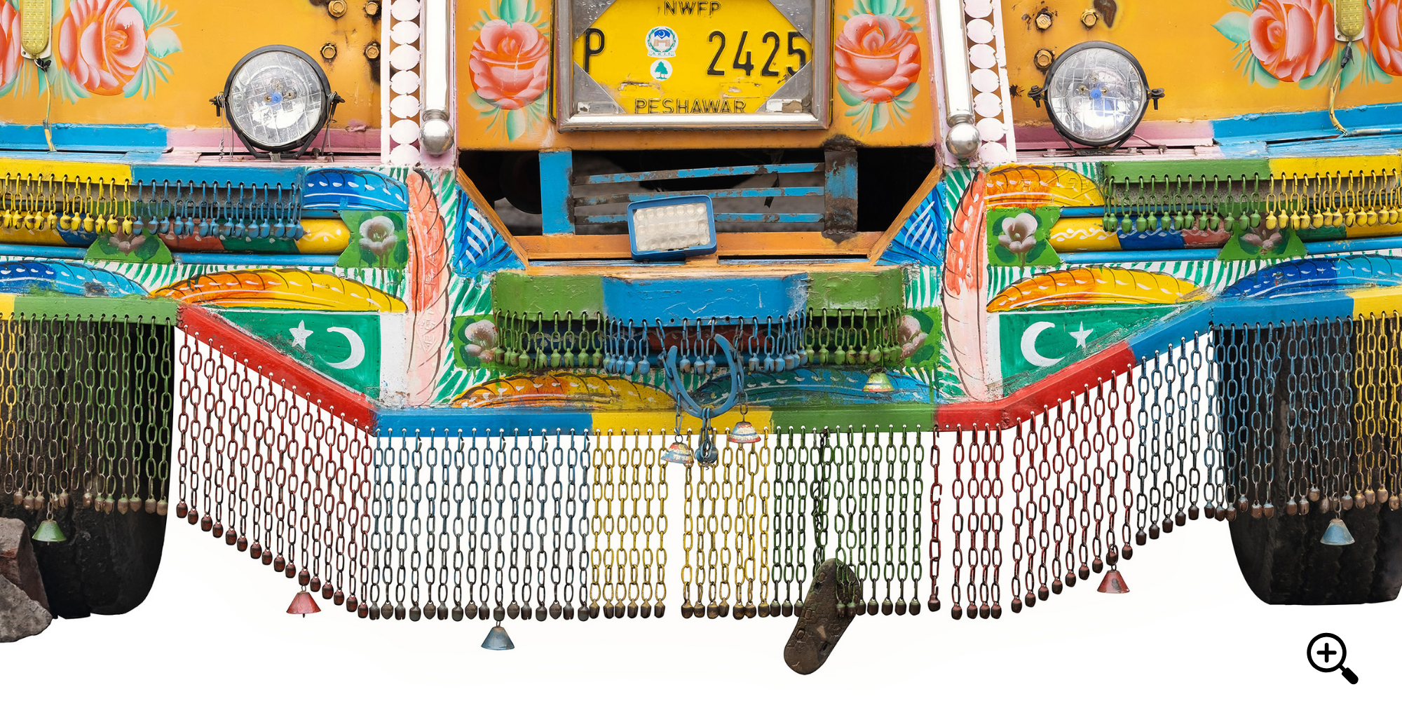 Die vordere Ansicht eines bunt bemalten Lastwagens, verziert mit Blumenmustern, pakistanischer Flagge und Zierketten, isoliert auf weißem Hintergrund.