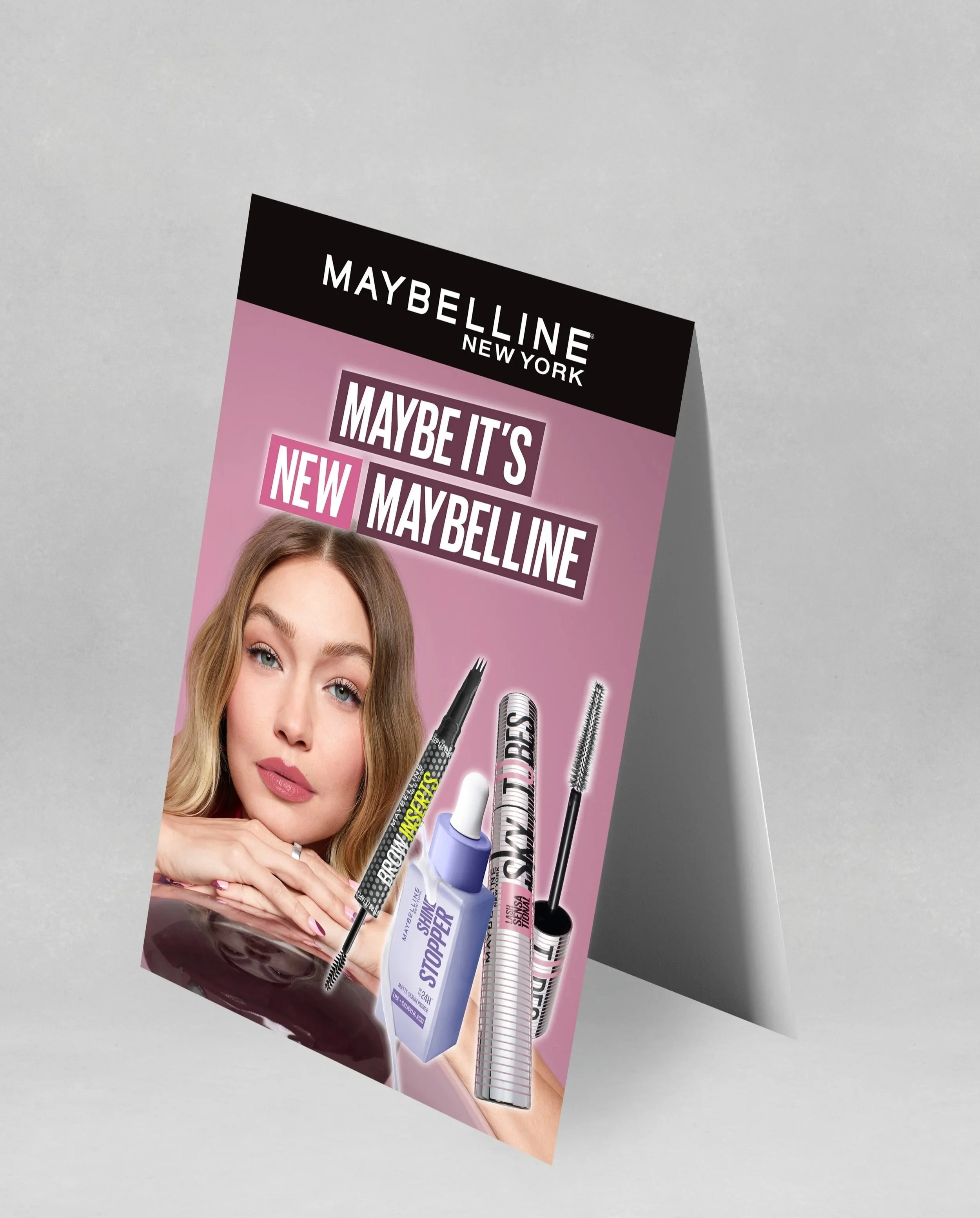 Maybelline new york advertisement featuring a woman with long wavy hair, promoting a Maybelline product line including mascara, eye primer, and other makeup items.