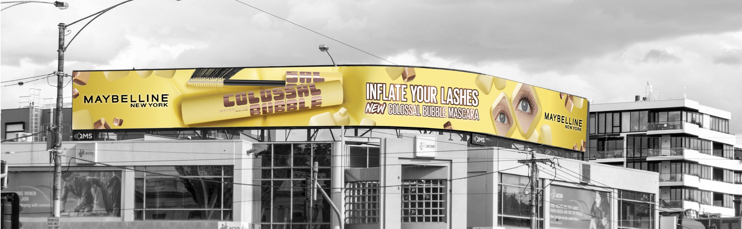 Billboard advertisement for Maybelline New York mascara with a yellow background, showing a mascara wand and two eyes with the hashtag #COLLAPSE in creative font, promoting the "Colossal Bubble" mascara.