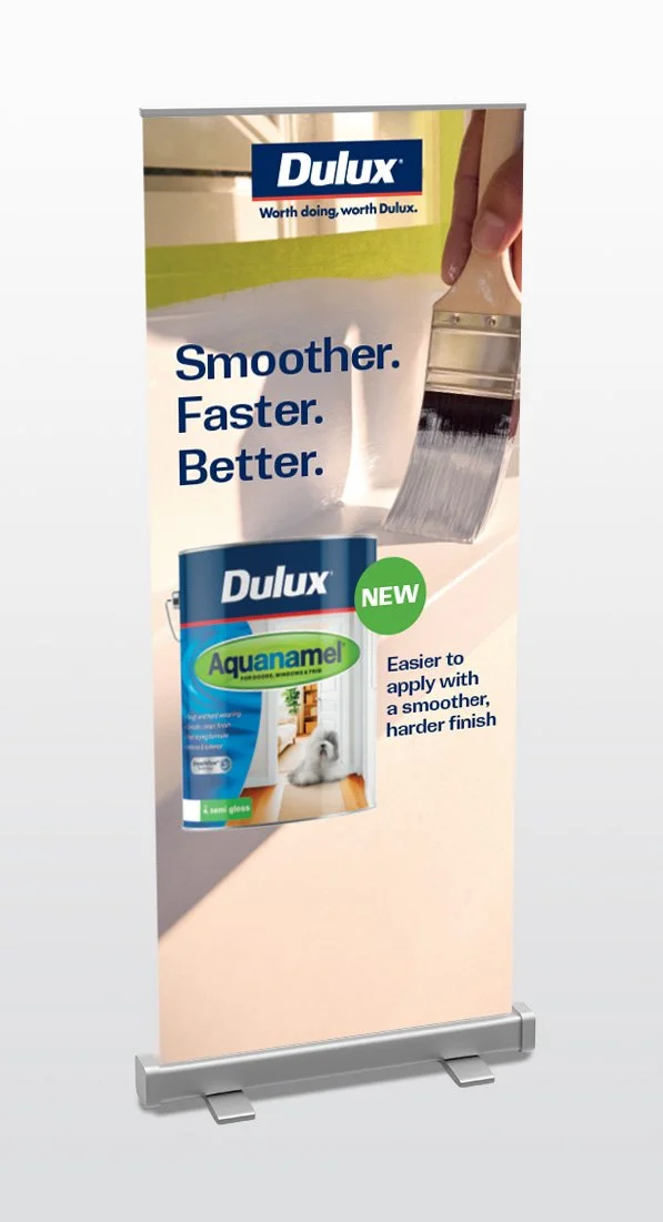A vertical promotional banner for Dulux paint featuring a paintbrush applying paint, with text highlighting the brand's paint products and features, including a new Aquanamel paint that is easier to apply with a smoother, harder finish.