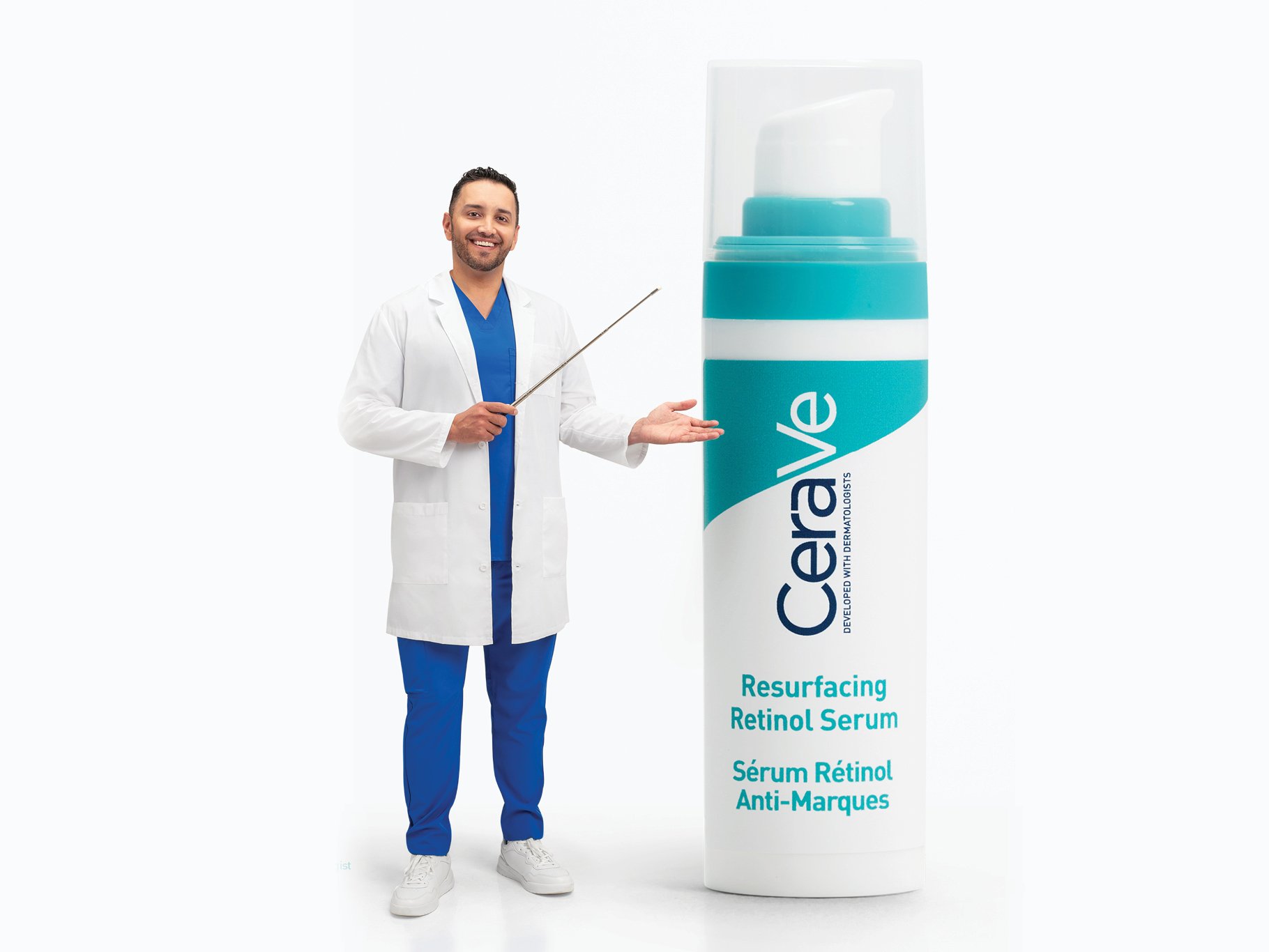 A male doctor wearing blue scrubs and a white lab coat, holding a pointer, standing next to a large product display for Cerave Resurfacing Retinol Serum, which features a teal and white design and text in English and French.
