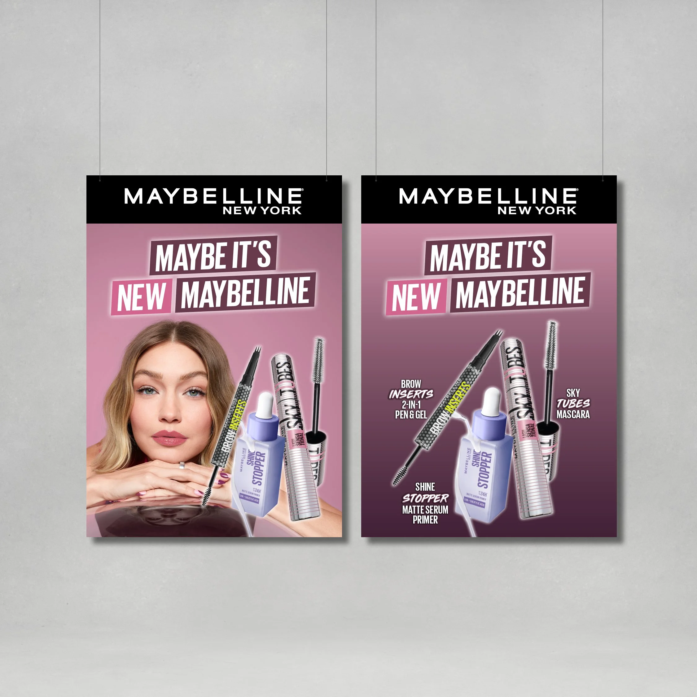 Two Maybelline New York makeup product posters on a gray wall, featuring a woman with blonde hair and various beauty products including mascara, primer, and top coat.
