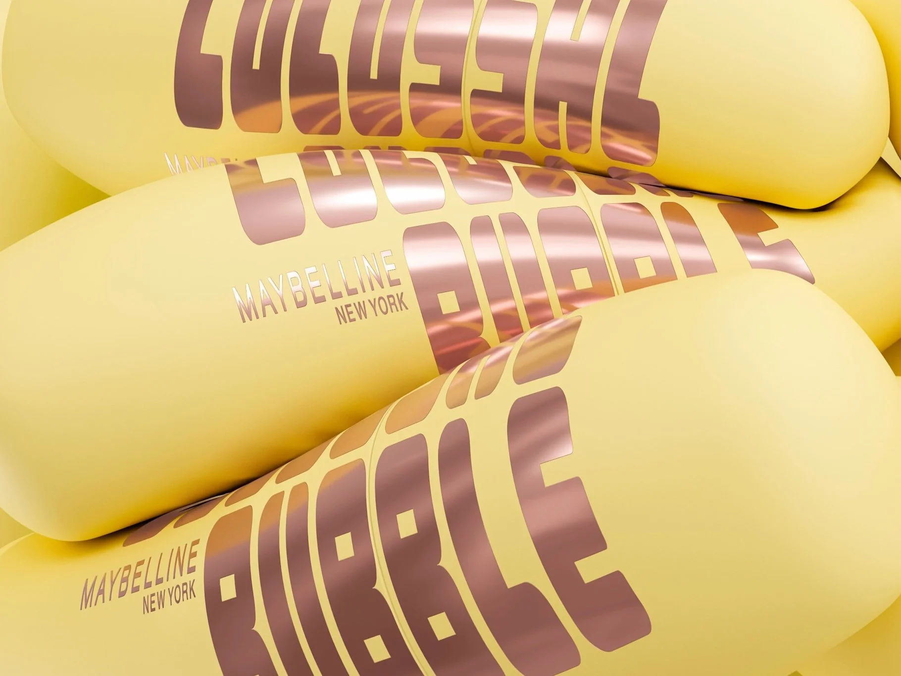 Close-up of yellow product packaging with rose gold metallic text that reads 'Maybelline New York' and other stylized text.