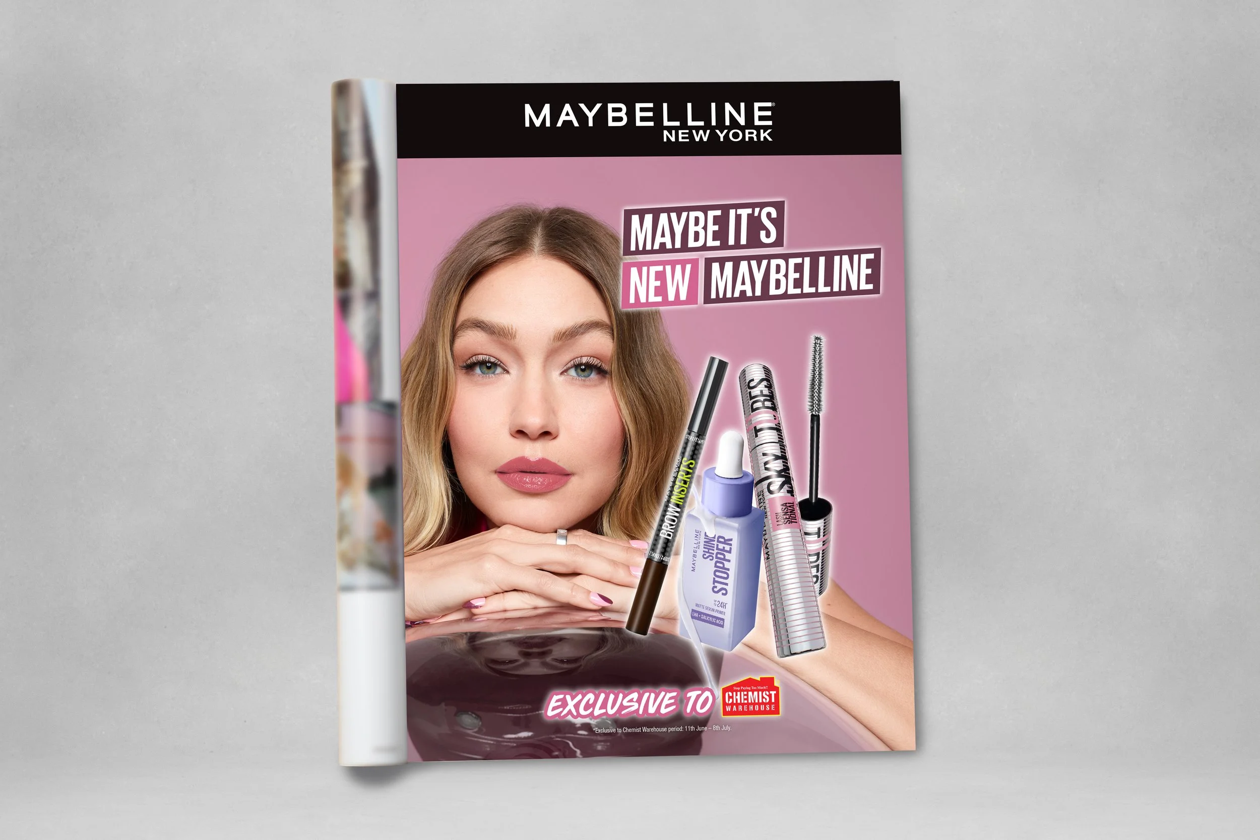 Maybelline New York advertisement featuring a woman with blonde hair and pink lipstick, showcasing various makeup products including mascara, lip gloss, and concealer, with a pink and black color scheme and promotional text.