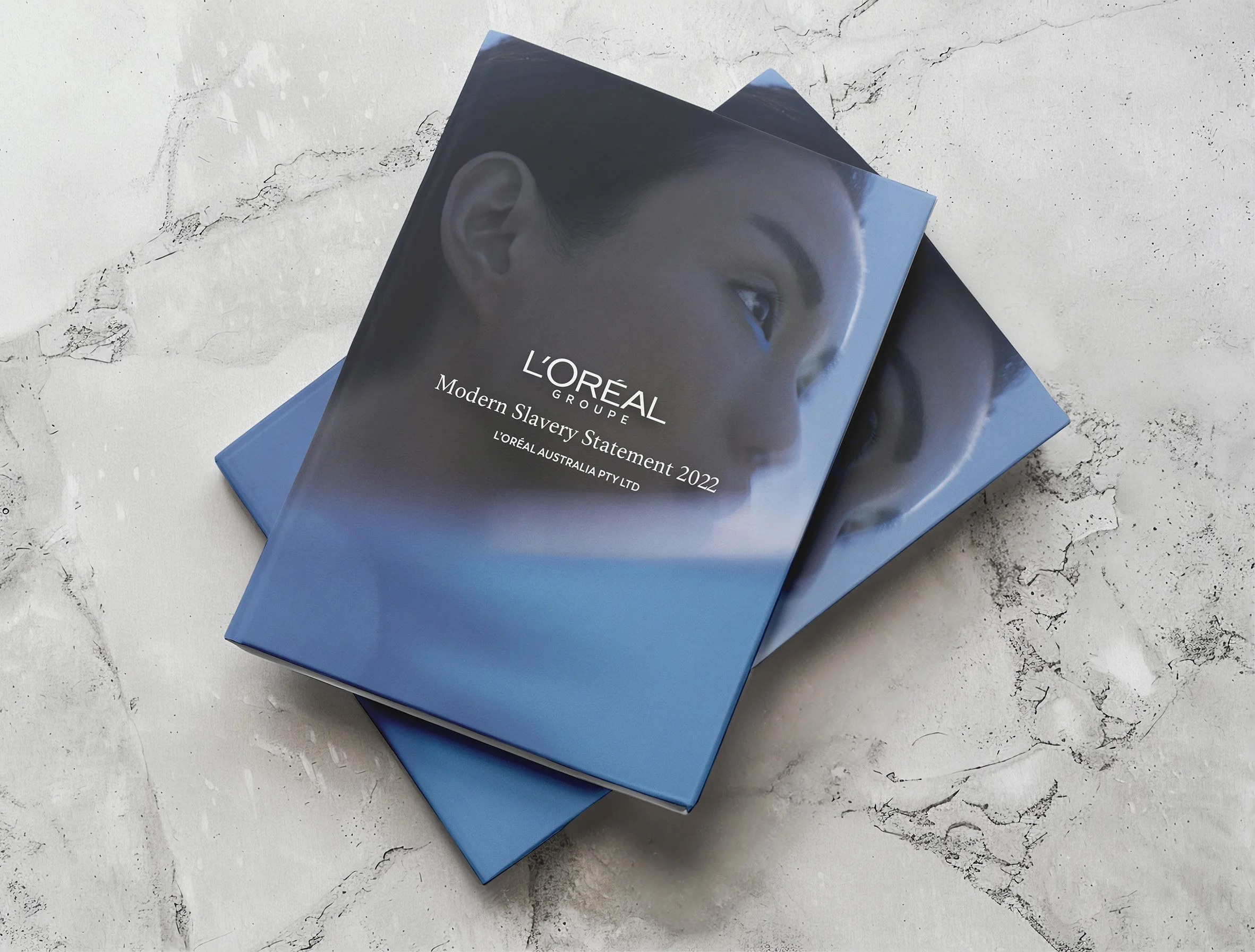 Booklets with artwork of a woman's face and the title 'L'ORÉAL GROUP Modern Slavery Statement 2022'.