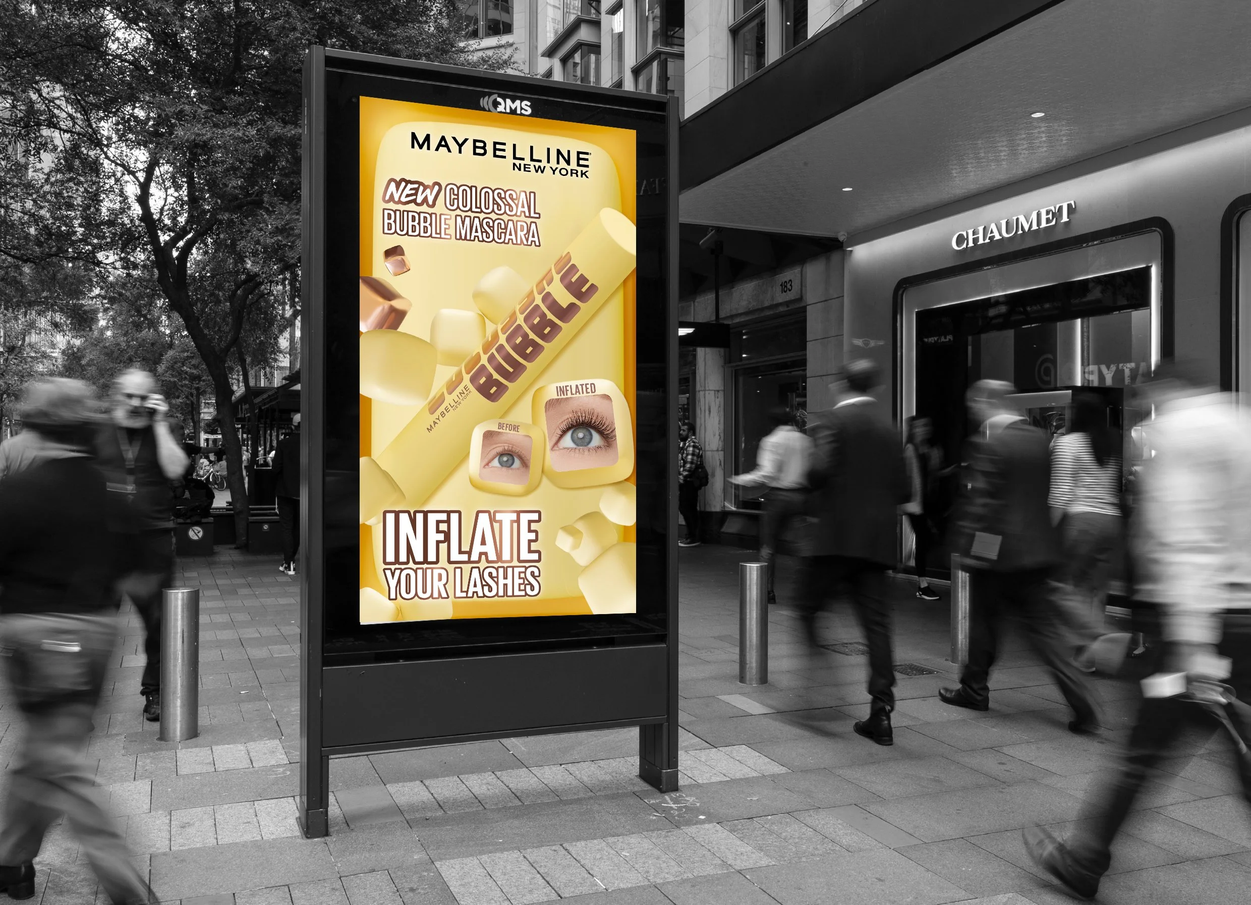 A digital billboard in an urban setting advertising Maybelline New York's new colossal bubble mascara, featuring images of eyes before and after applying the mascara, and a close-up of the mascara wand with bubble-like applicator.