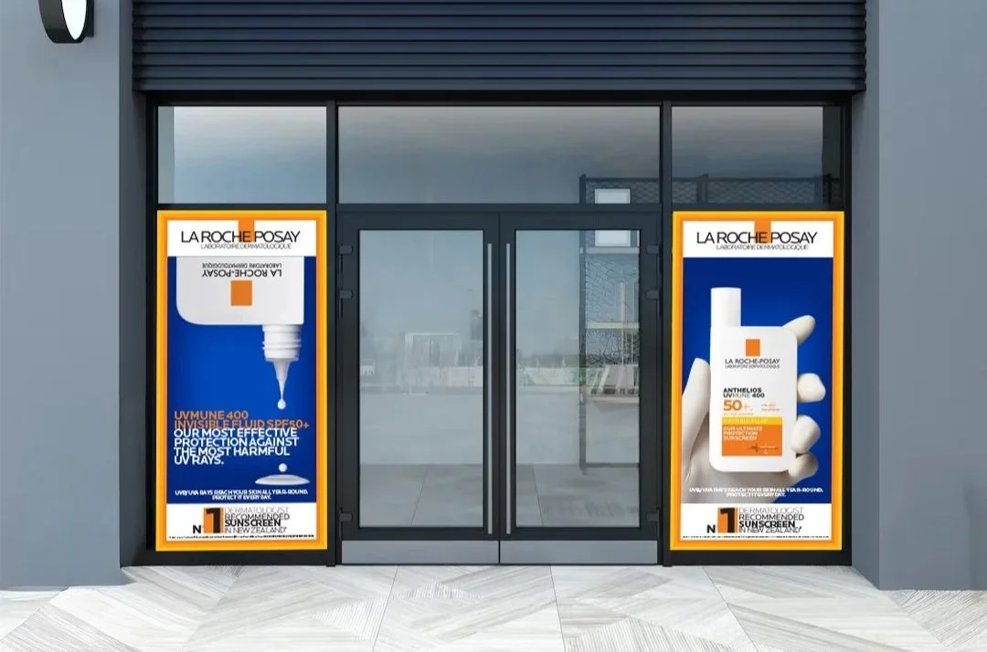 Two posters advertising La Roche-Posay skincare products displayed outside a store entrance with glass doors.