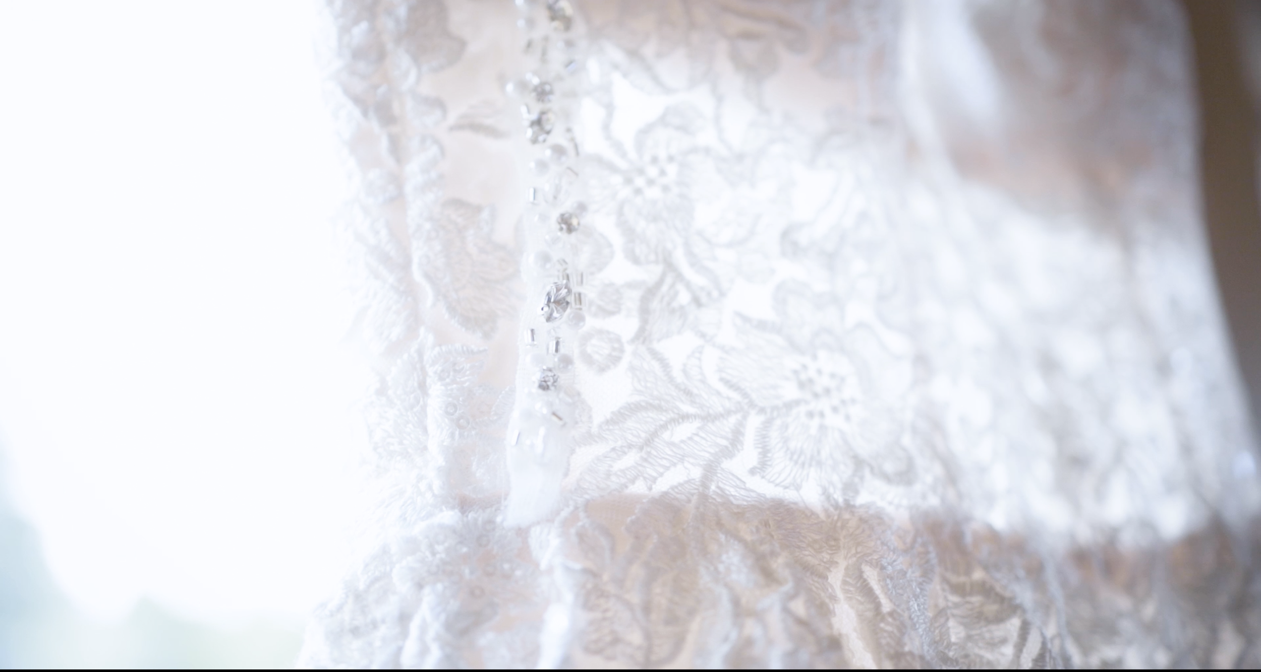 Close-up of a lace wedding dress with intricate embroidery and beadwork.