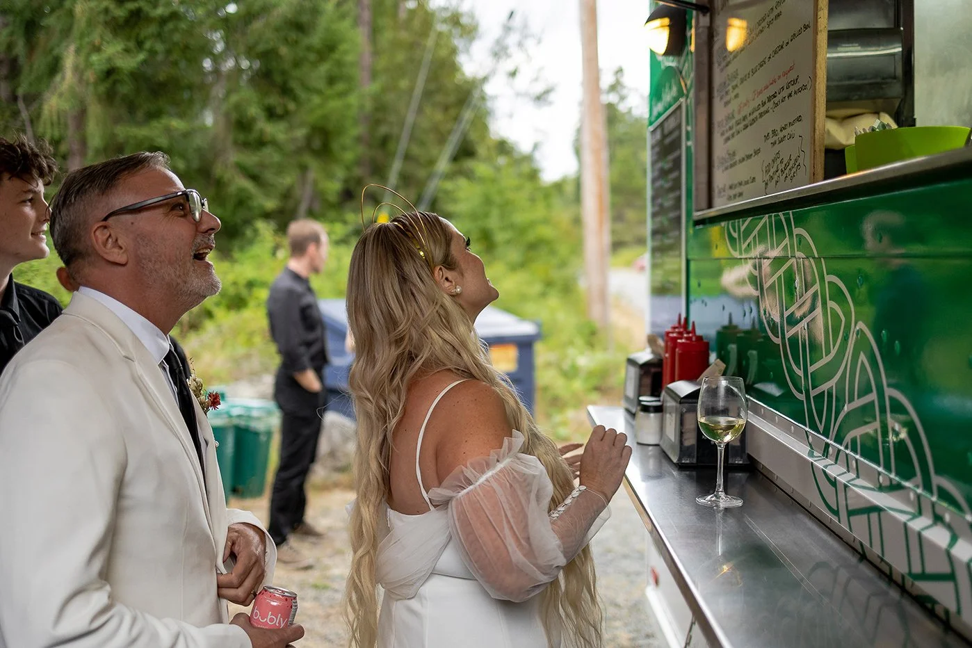 People in formal attire ordering food from a food truck outdoors.