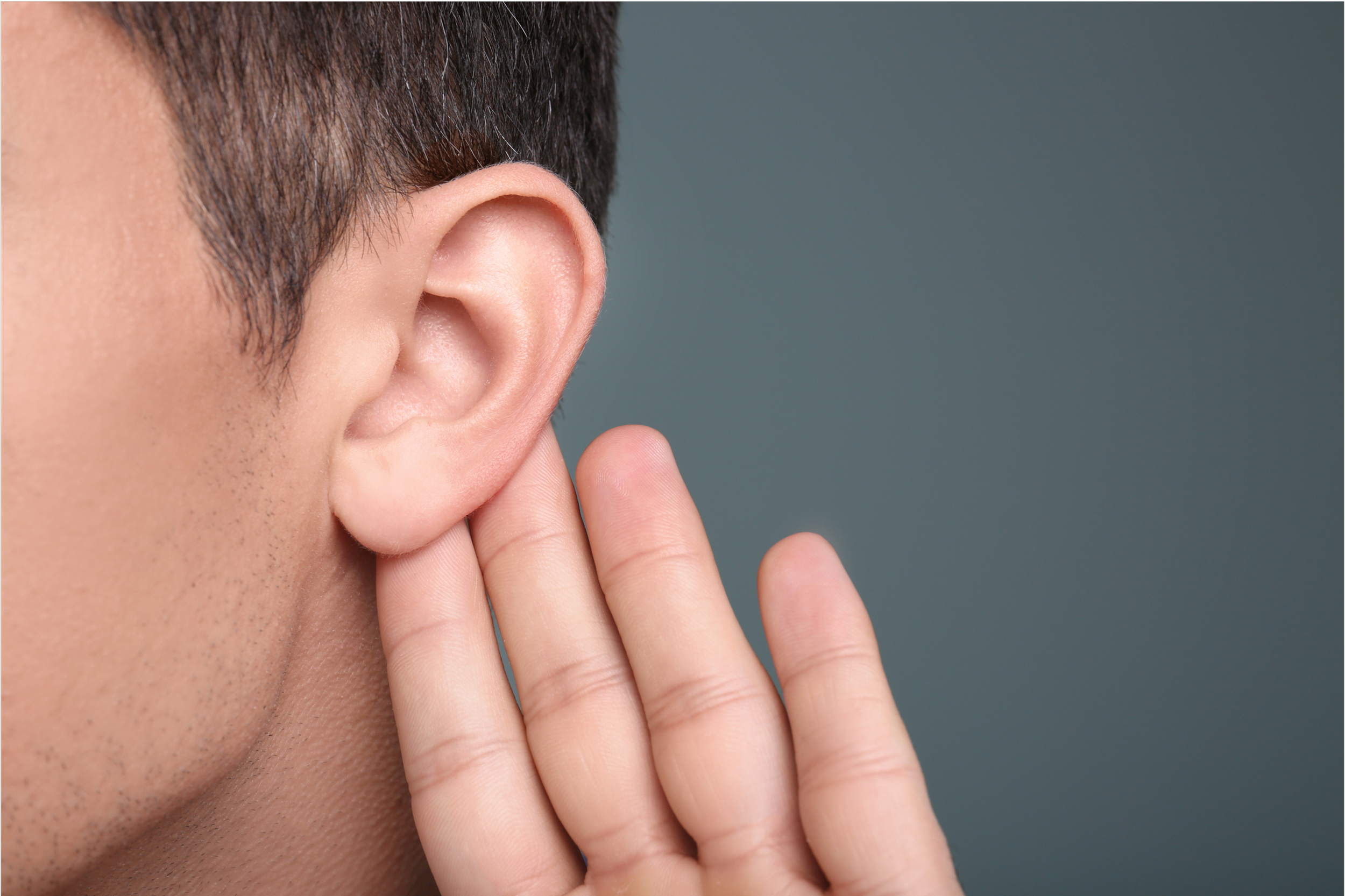 A person cupping their hand behind their ear, listening carefully.