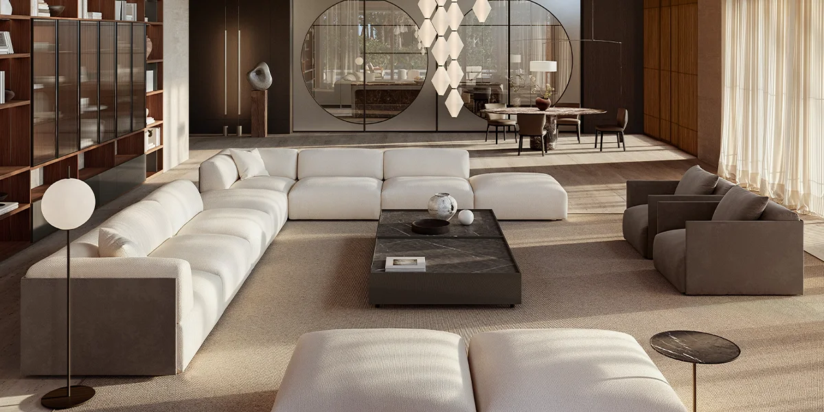 Modern living room with white sectional sofa, two gray armchairs, black marble coffee table, and minimalist decor, including sculptures, vases, and lighting fixtures.