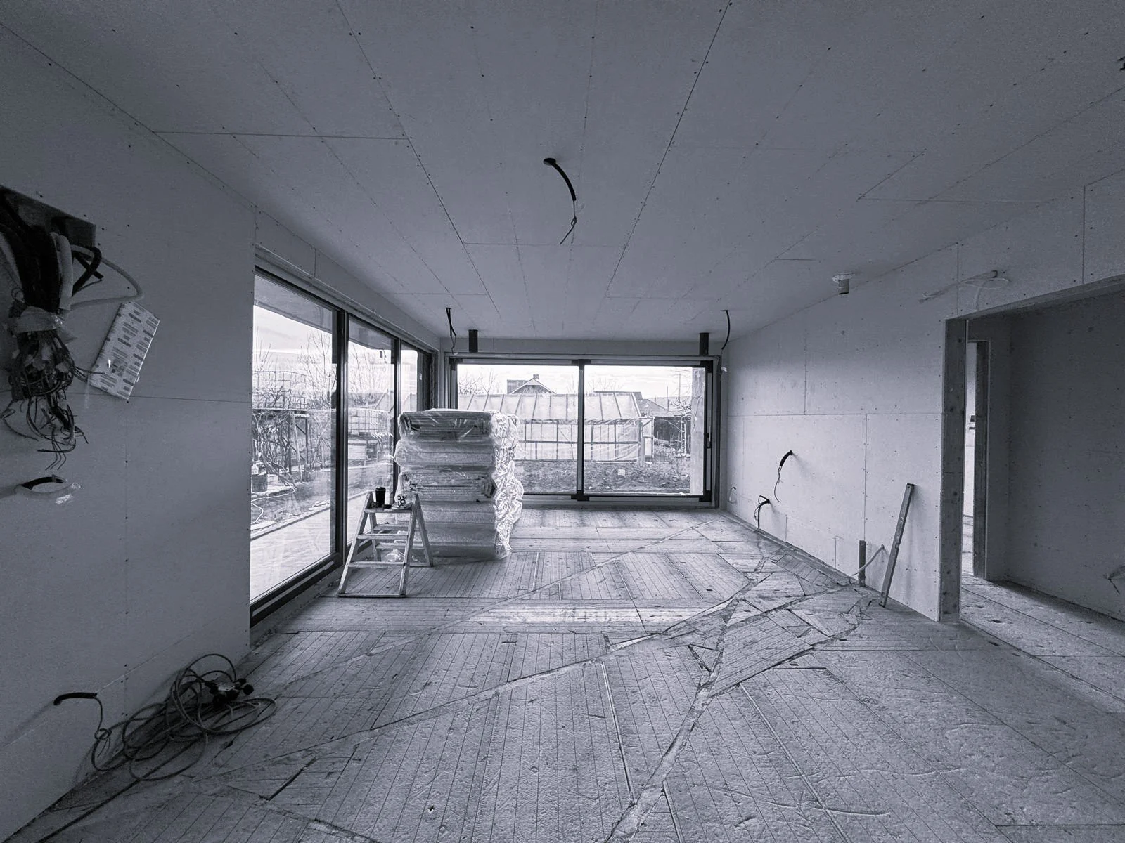 Unfinished room with large glass sliding doors, construction materials, and wiring exposed on ceiling and walls.