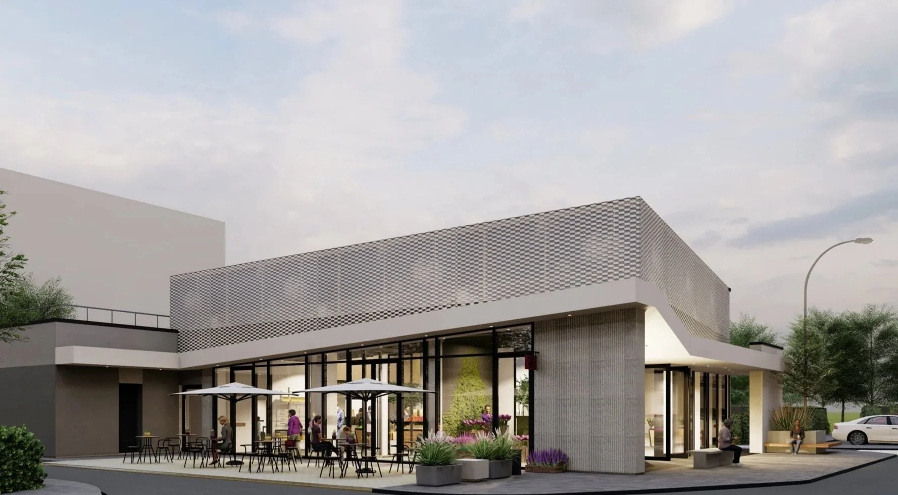 A modern building with outdoor seating and patio umbrellas, people sitting and walking, trees, a parked car, and a cloudy sky.