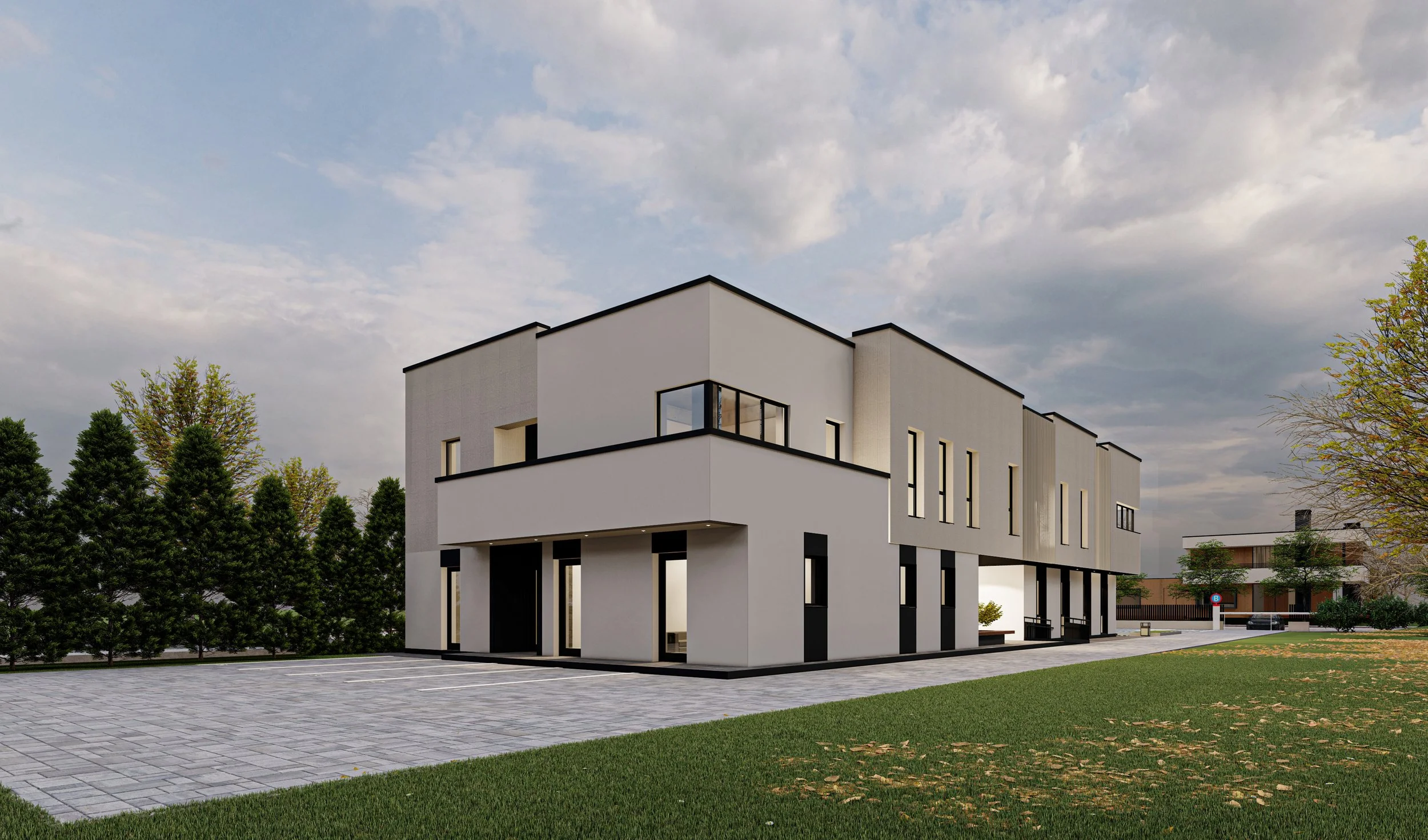 Modern white multi-story building with large windows, sidewalk, green grass, and trees under a cloudy sky.