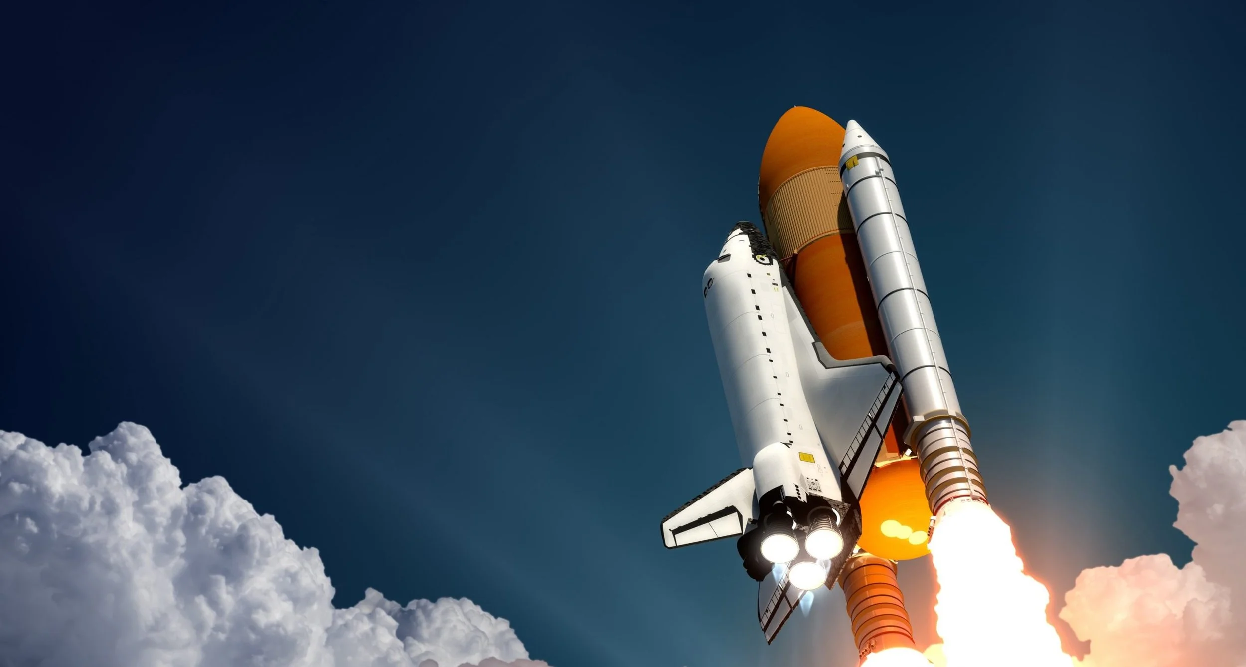 Un lanceur spatial en train de décoller avec du feu et des fumées, le ciel est bleu avec des nuages blancs à la base.