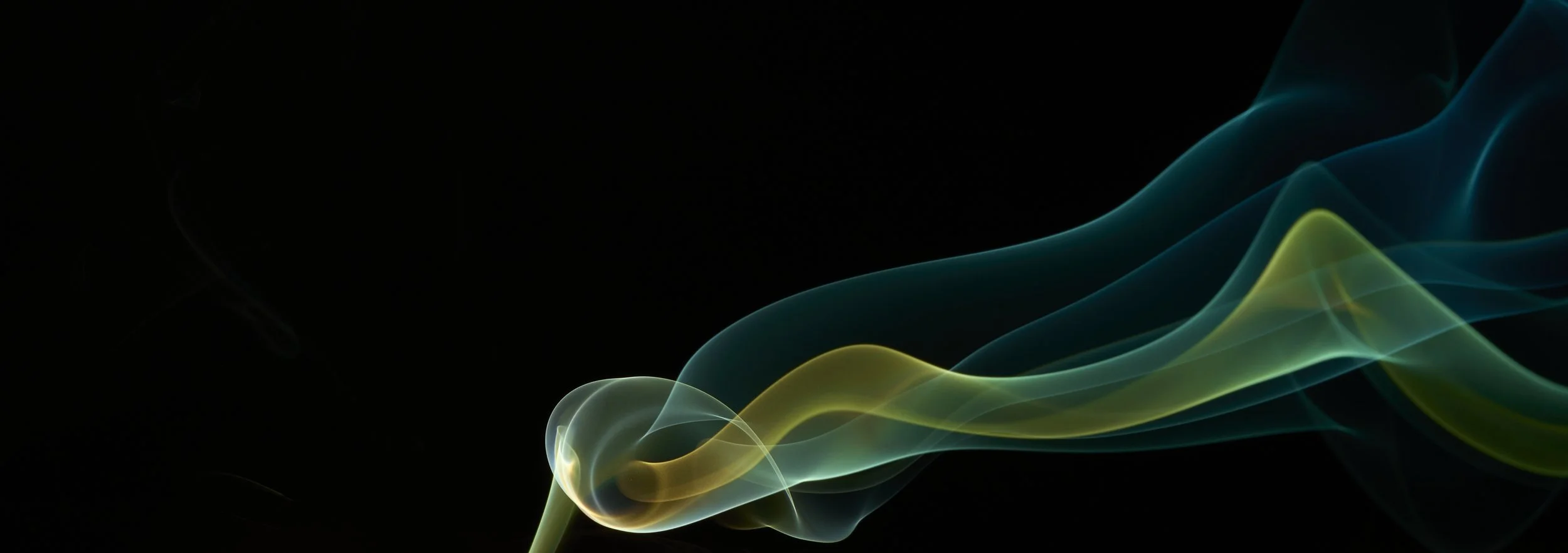 Colorful wisps of smoke or light flowing on a dark background in shades of blue, green, and yellow.