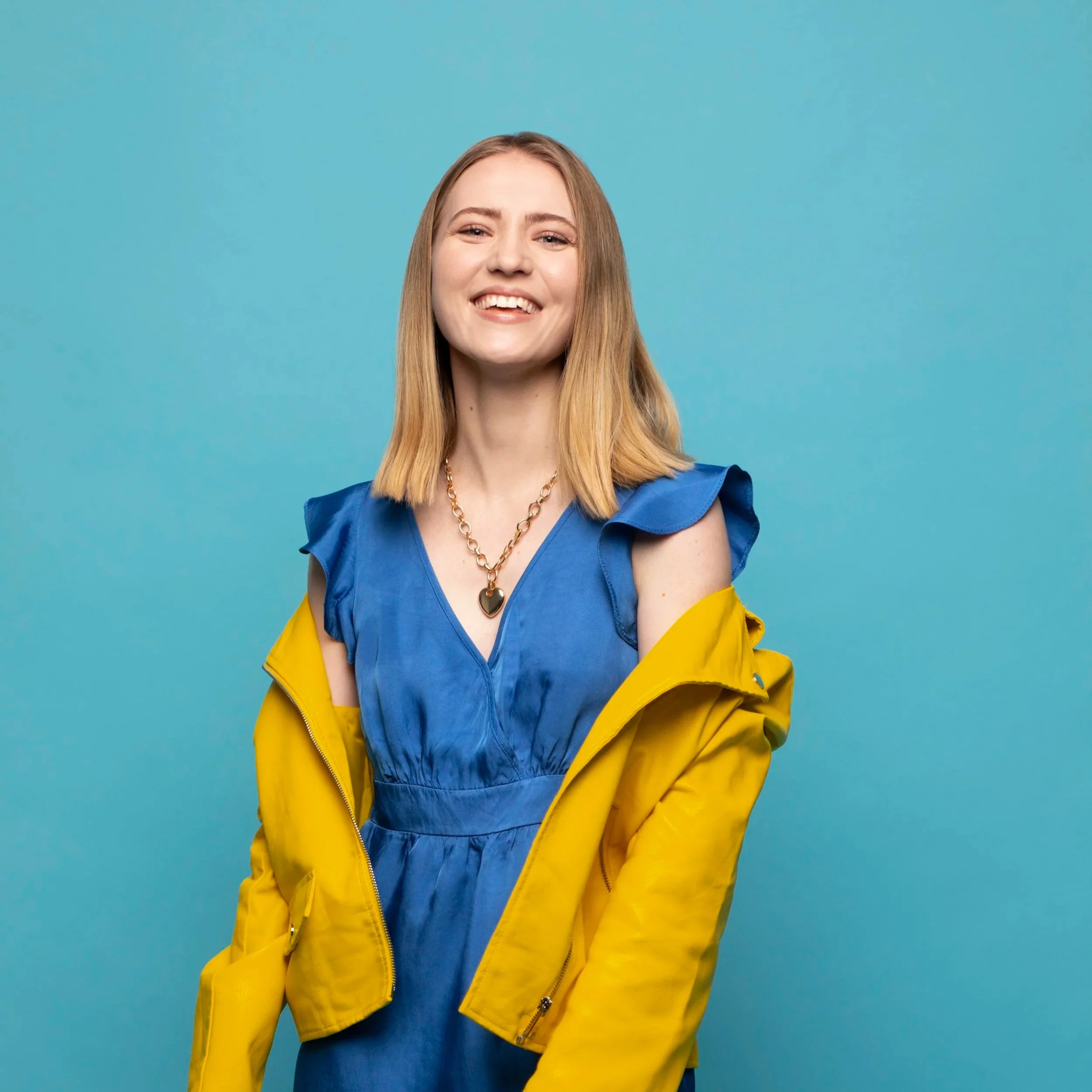 Smilende kvinne med blå kjole og gul jakke