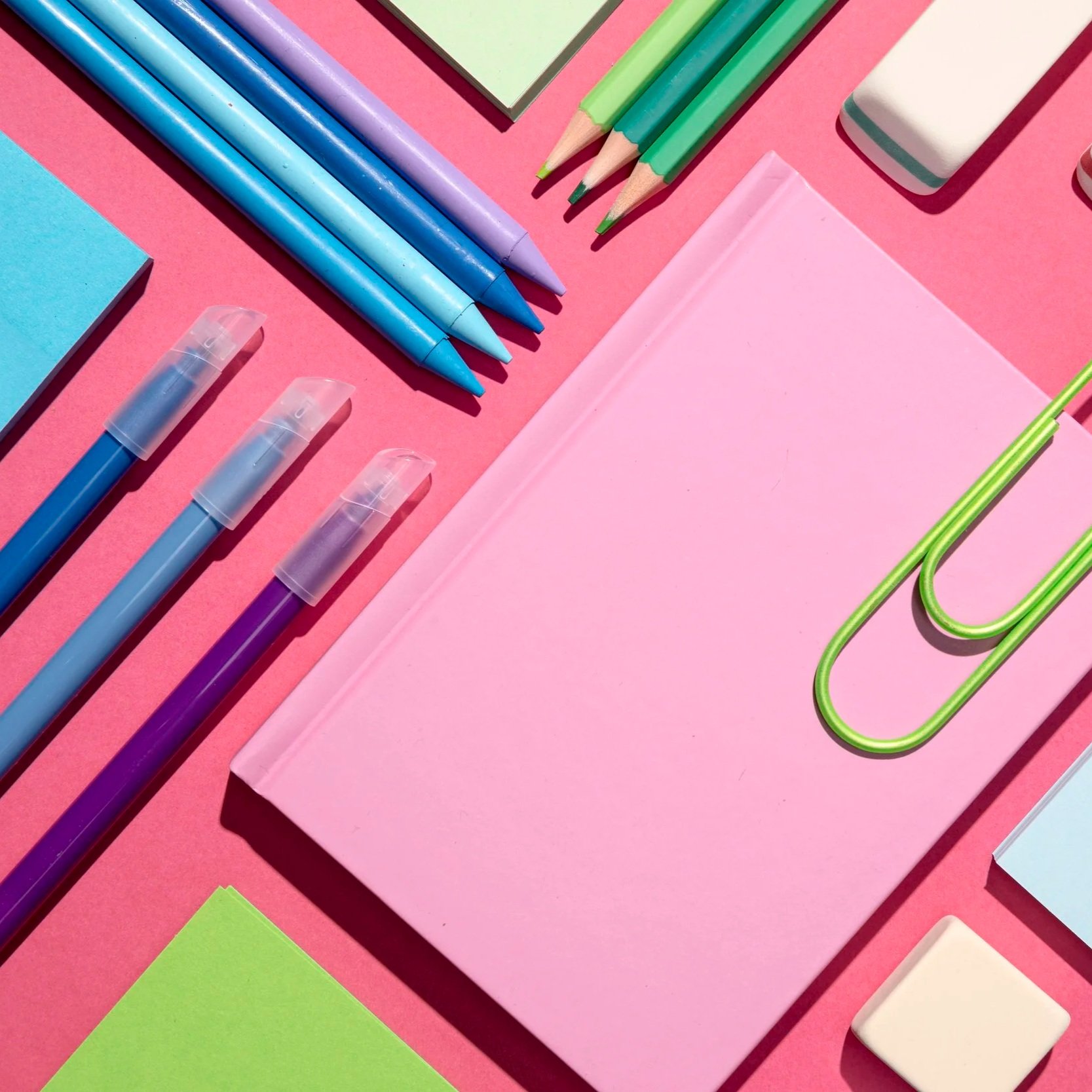 Skrivebøker, penner og viskelær liggende flatt