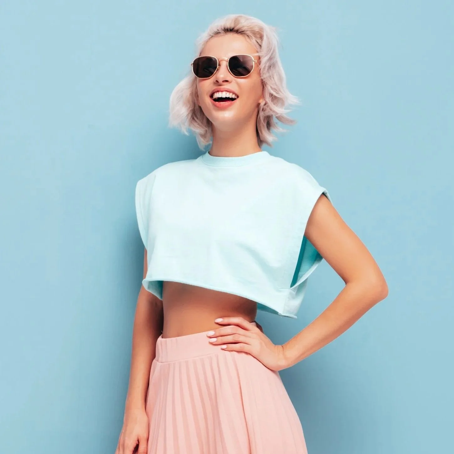 Smilende ung kvinne med solbriller og sommerklær