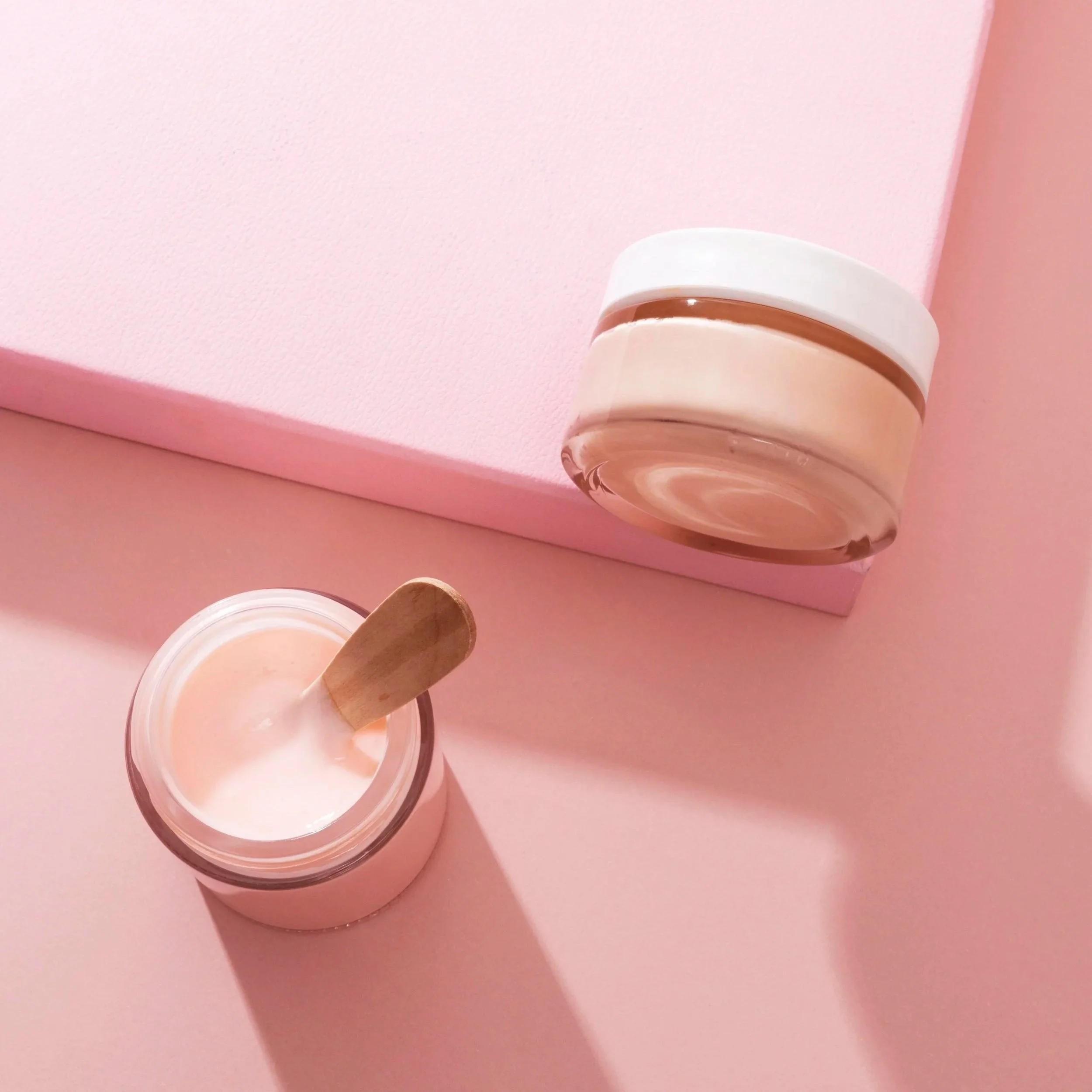 Krukker med krem og rosa bakgrunn