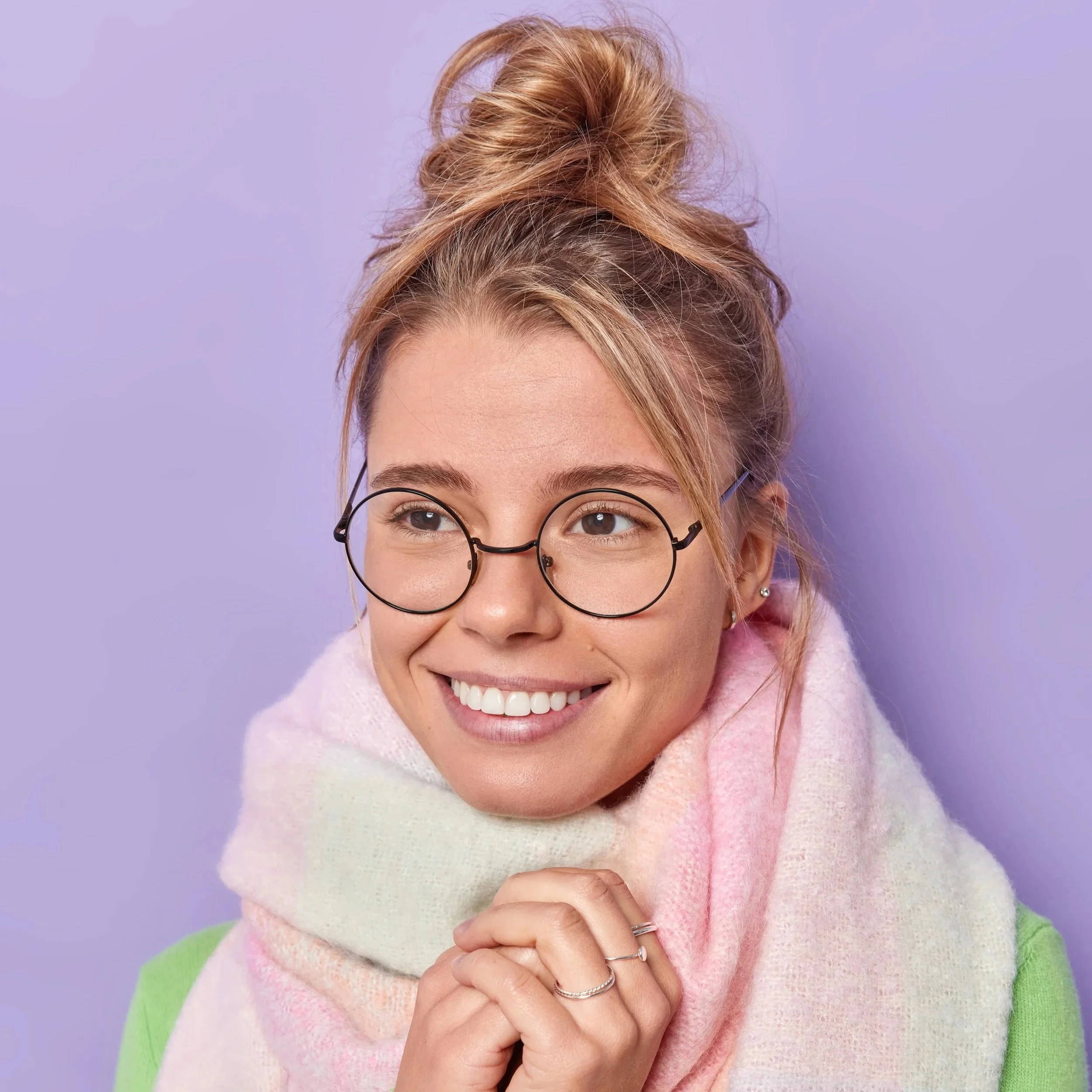 Ung, blond kvinne med runde briller og skjerf i pastellfarger