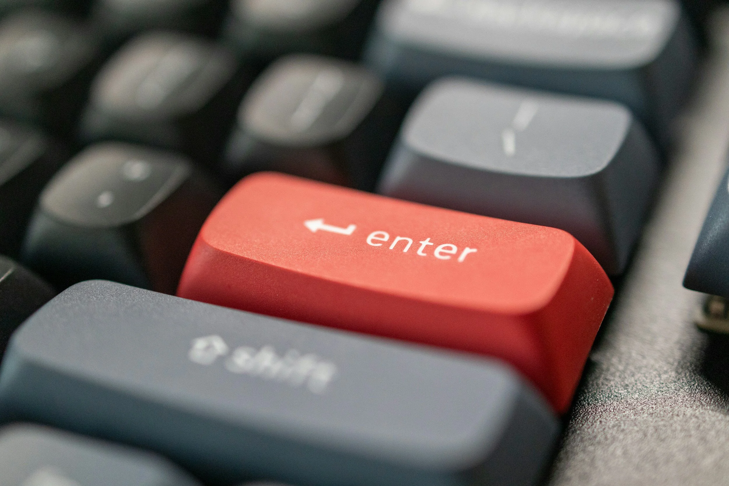 Close-up of a computer keyboard with a red 'Enter' key in focus.
