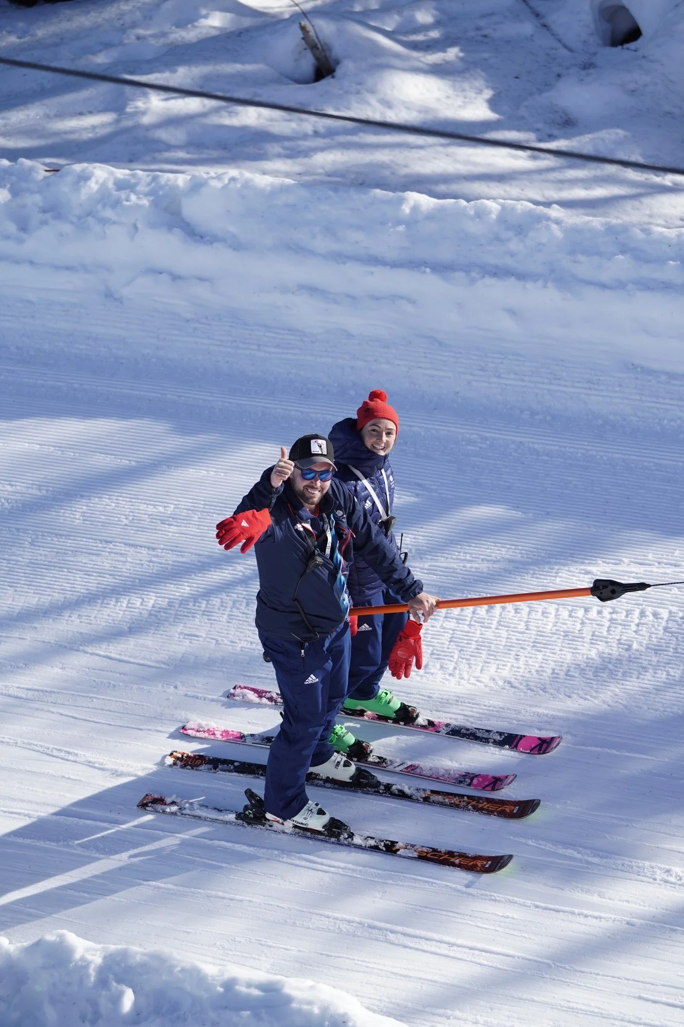 A male and female ski coach on a t-bar lift on the snow