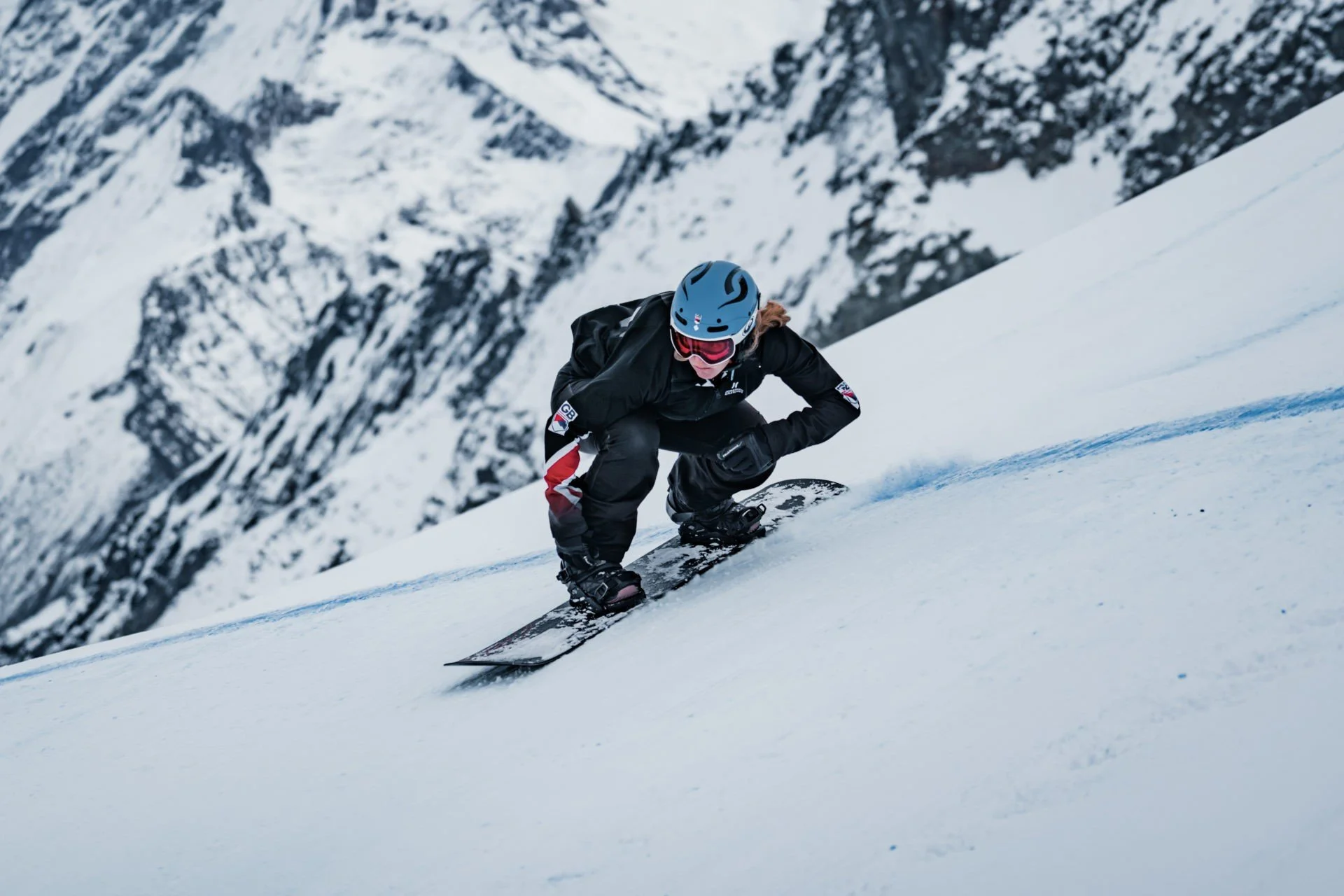 A female snowboarder riding a boardercross course on snow