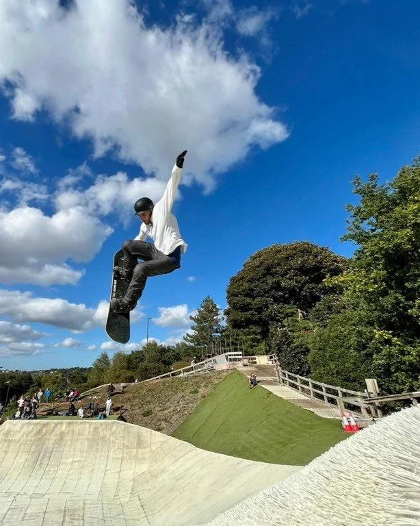 A snowboarder doing a trick of a jump at a dry slope in England