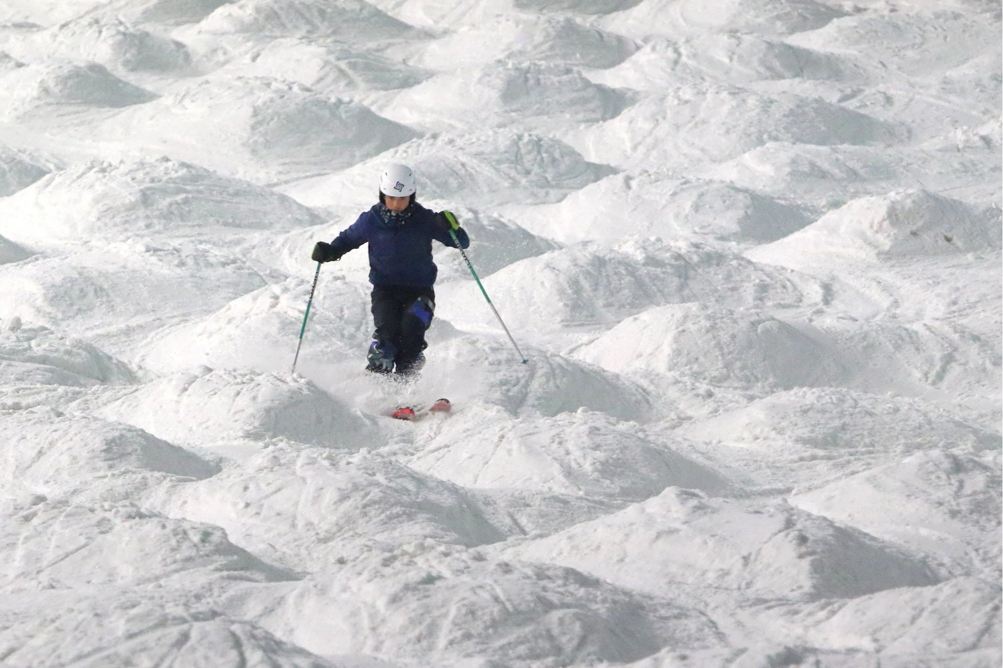 A male skier tackles moguls at indoor snow centre