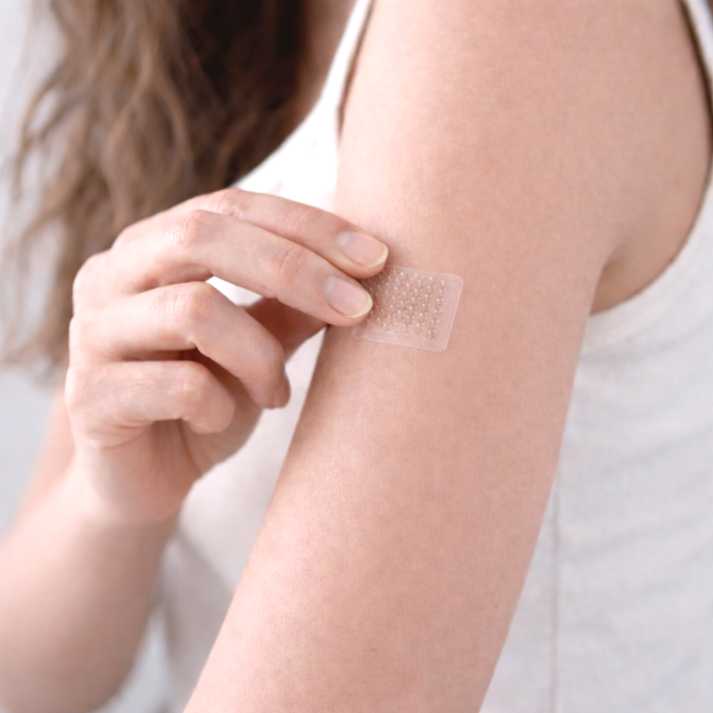 A person applying a patch to their upper arm.