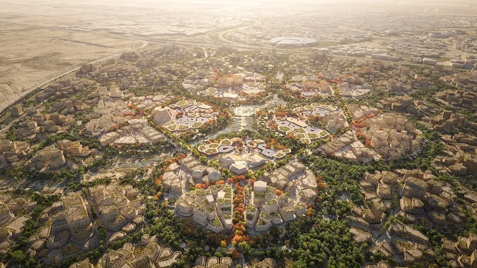 Une vue aérienne d'un complexe architectural moderne avec des bâtiments séparés par de la verdure et des chemins, le tout dans un environnement urbain étendu.