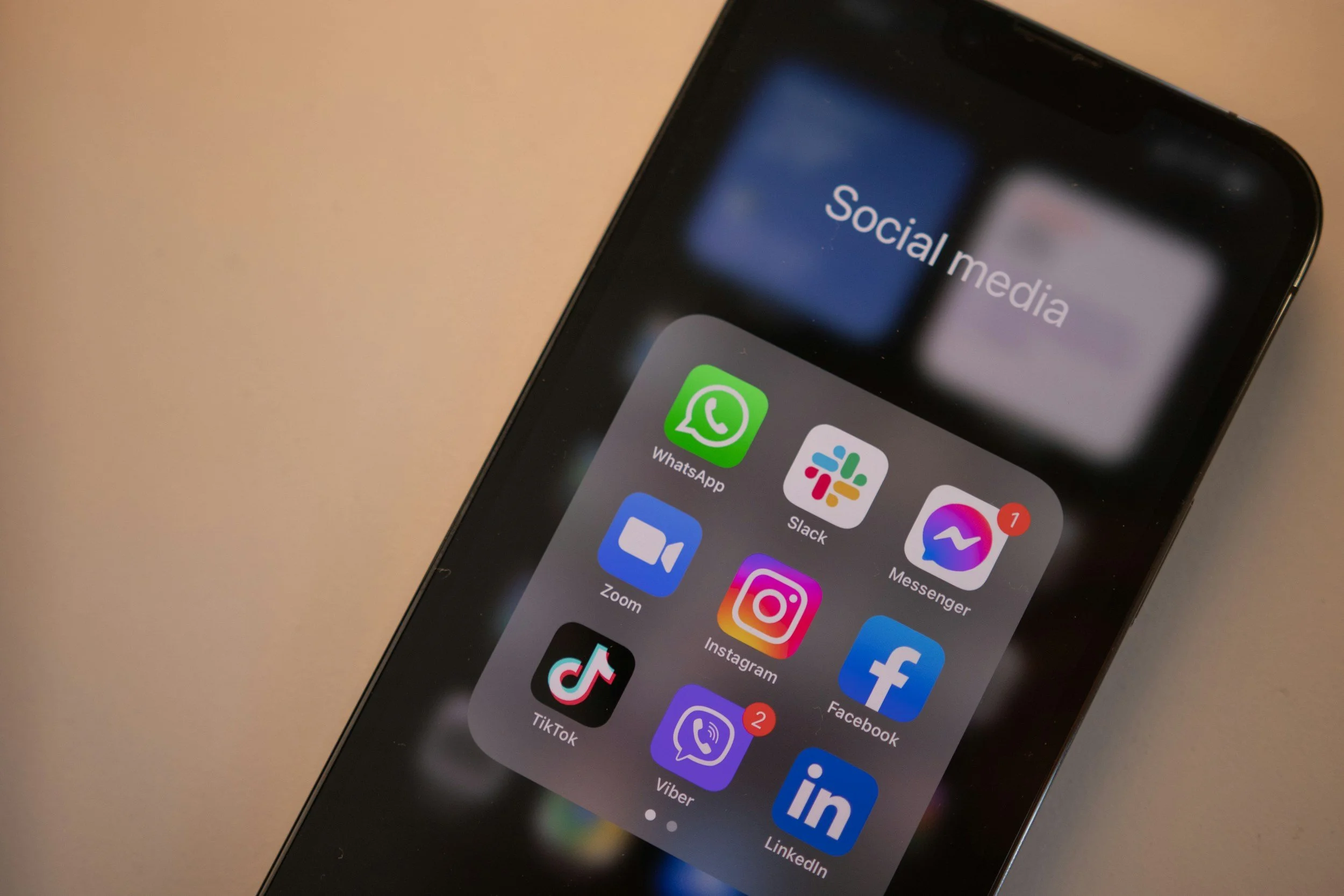Smartphone mit Social-Media-Apps in einem Ordner, darunter WhatsApp, Slack, Messenger, Zoom, Instagram, Facebook, TikTok, Viber, LinkedIn, alle auf dem Bildschirm sichtbar.