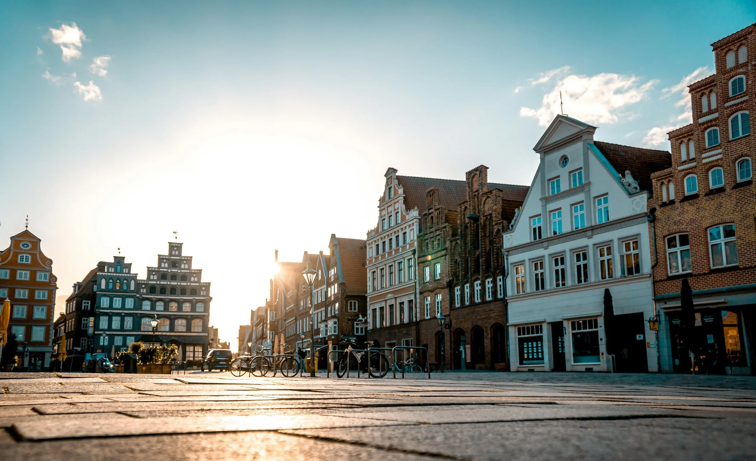 Bunte historische Gebäude in Lüneburg, Landkreis Lünebuerg, Sonnenuntergang, Fahrradständer, gepflasterte Straße.