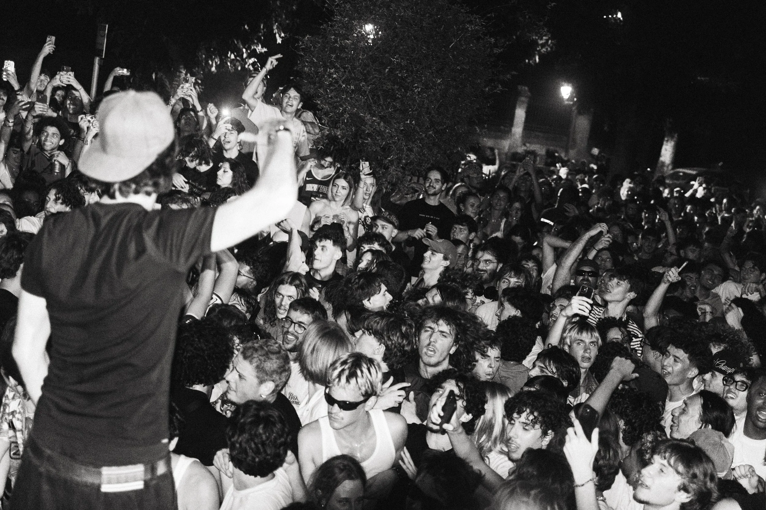 Une foule dense de personnes lors d'un événement, certaines prennent des photos avec leur téléphone, beaucoup sourient et semblent excitées.