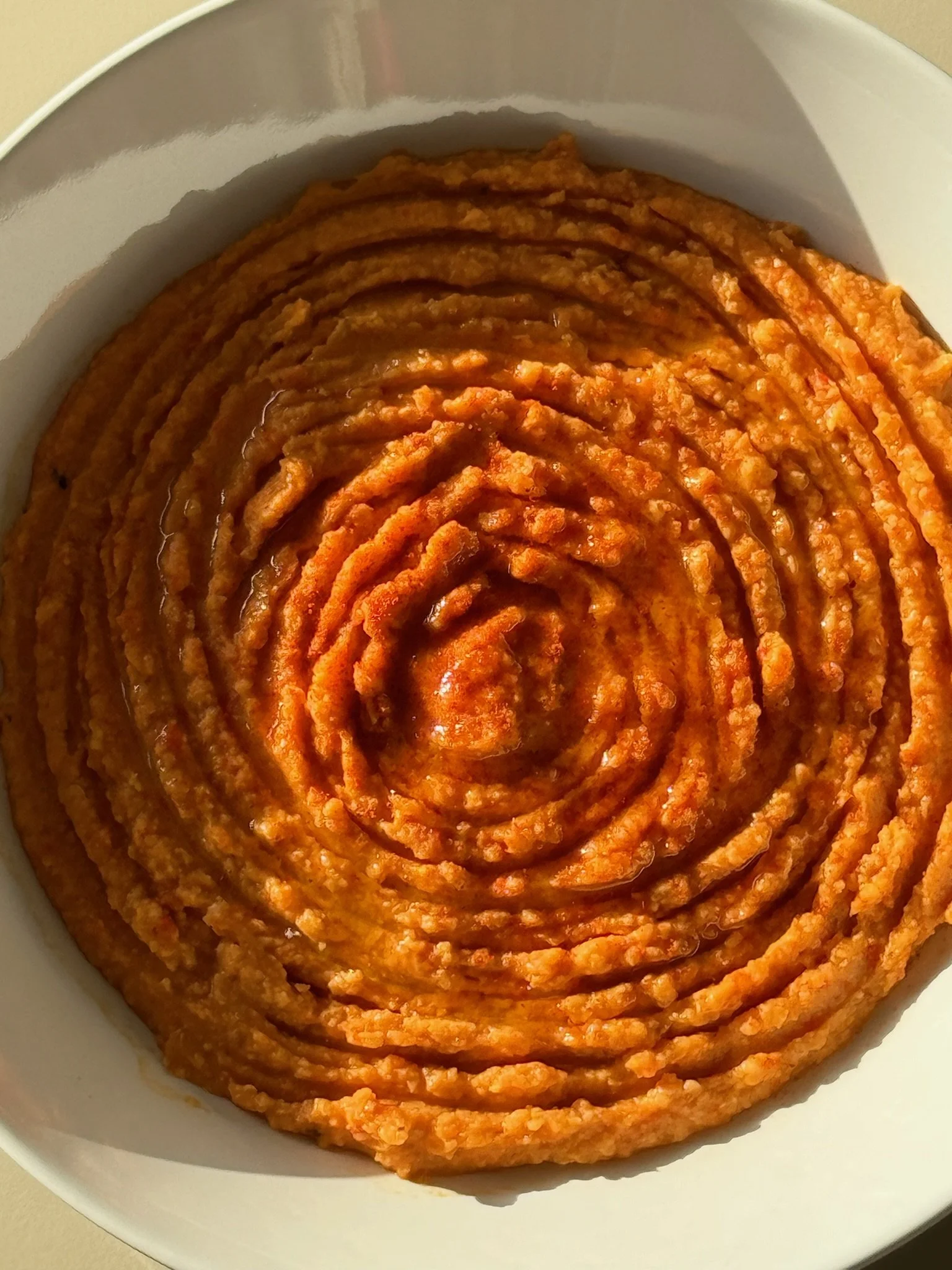 Close-up of a bowl of bright orange, pureed sweet potato mash with visible texture.