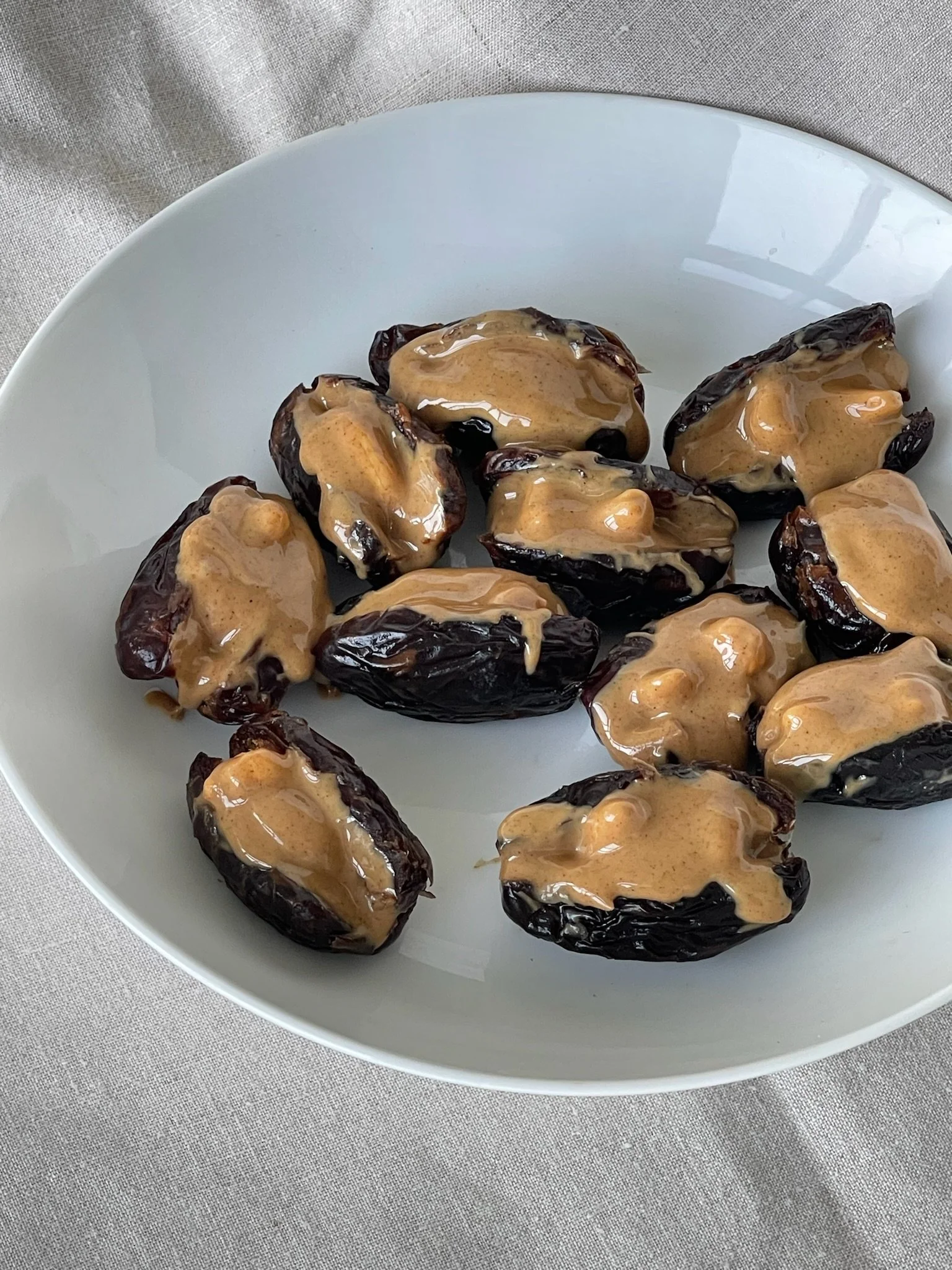 Platter of dates stuffed with almond and topped with peanut butter.