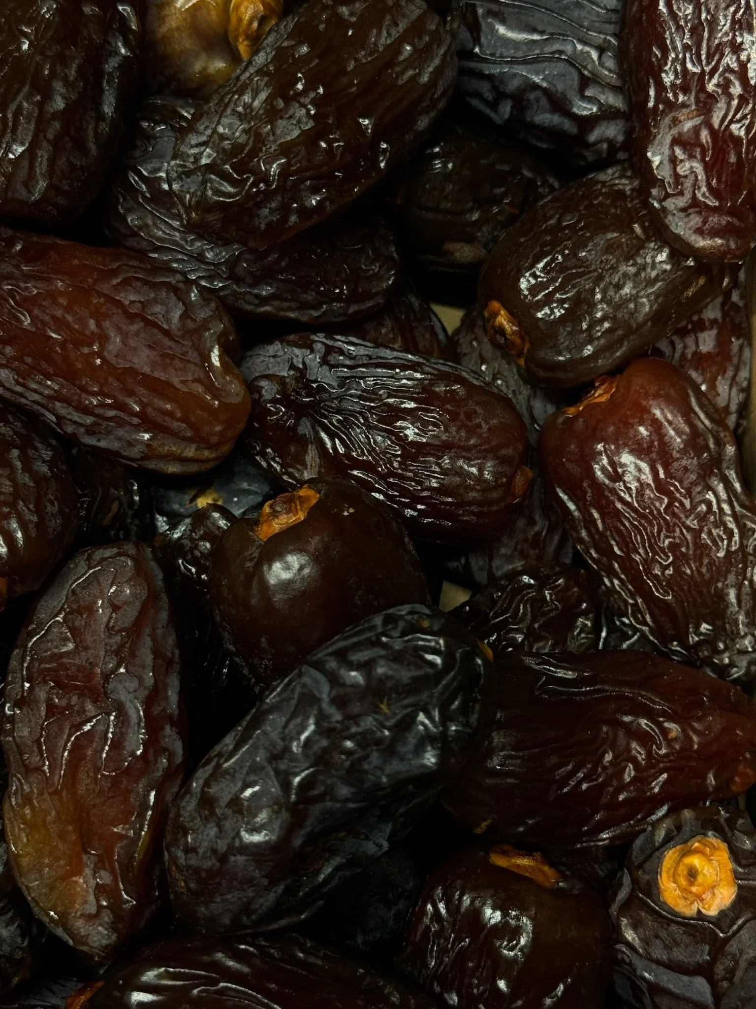 A close-up photo of a bunch of ripe dates with dark brown, wrinkled skin.