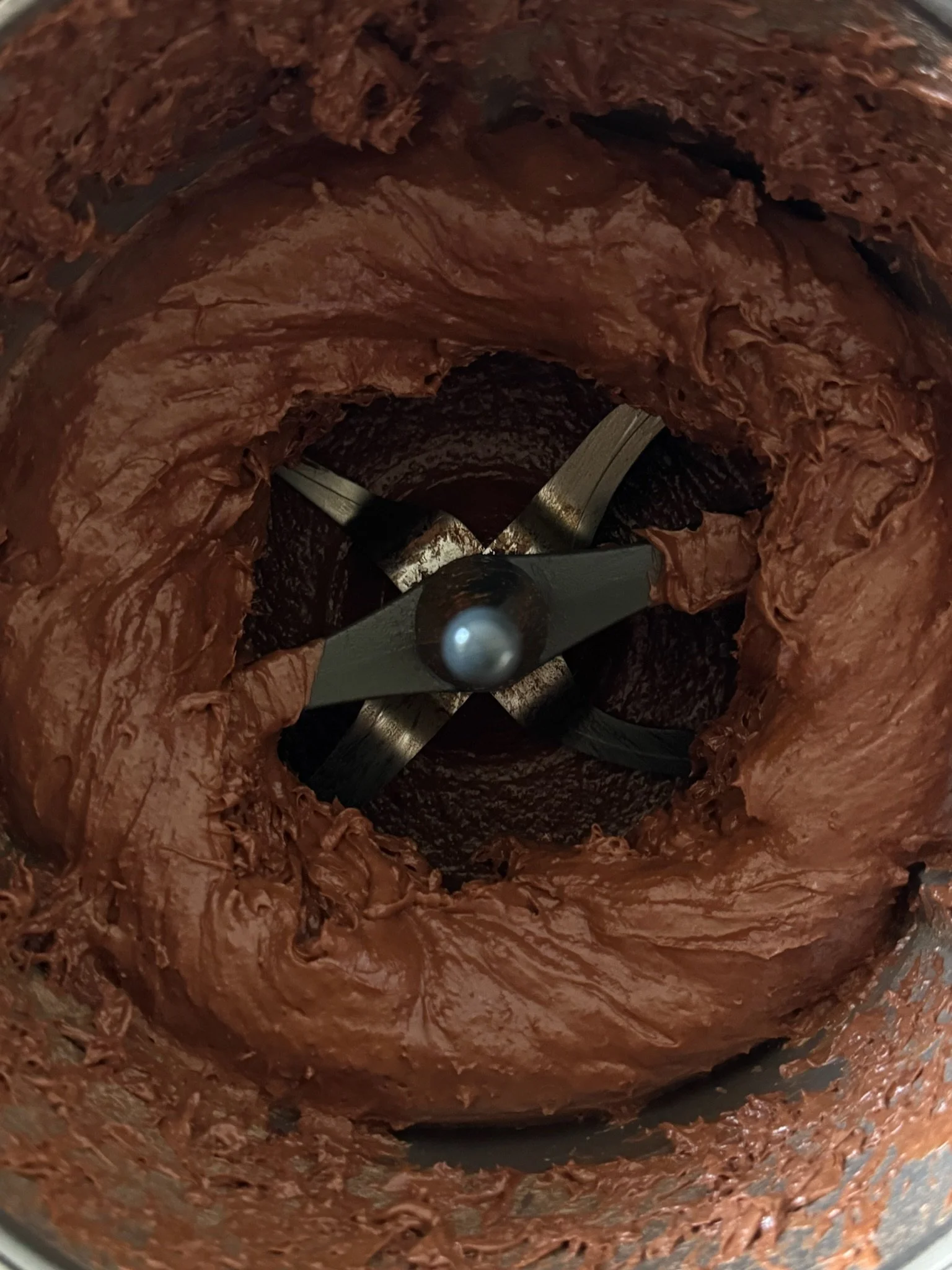 Close-up view of a blender mixing chocolate spread inside a container.